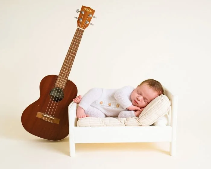 Newborn asleep beside a ukulele