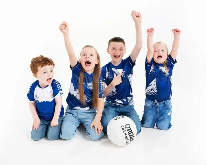 Four children in GAA jerseys with a football