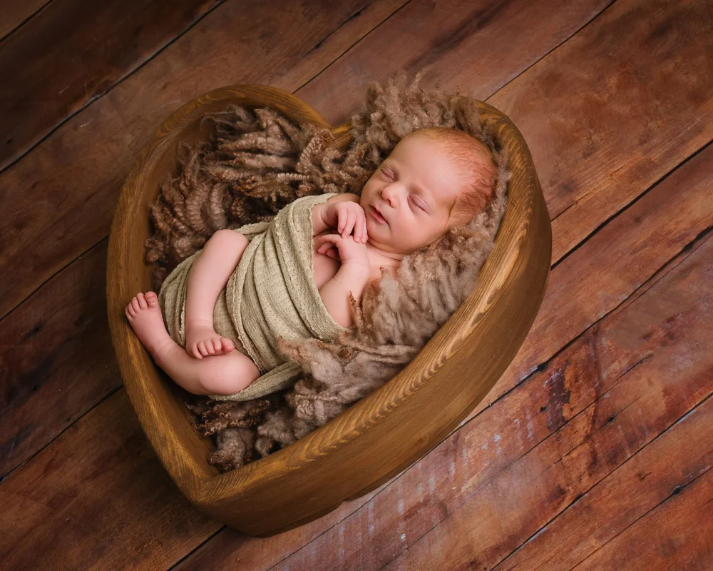Newborn asleep in a wooden heart