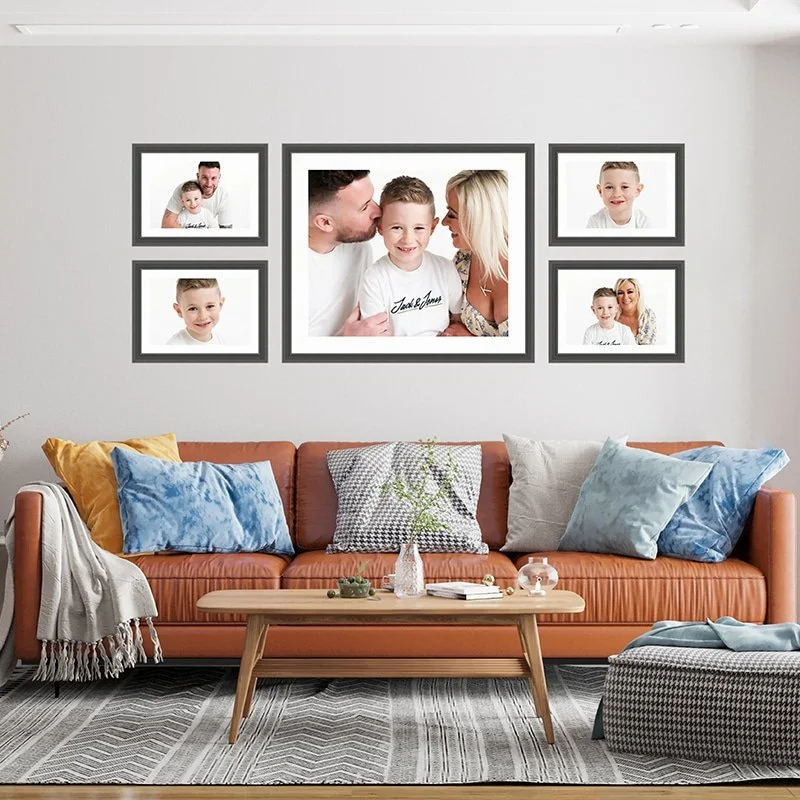 Collection of framed family portraits above a sofa