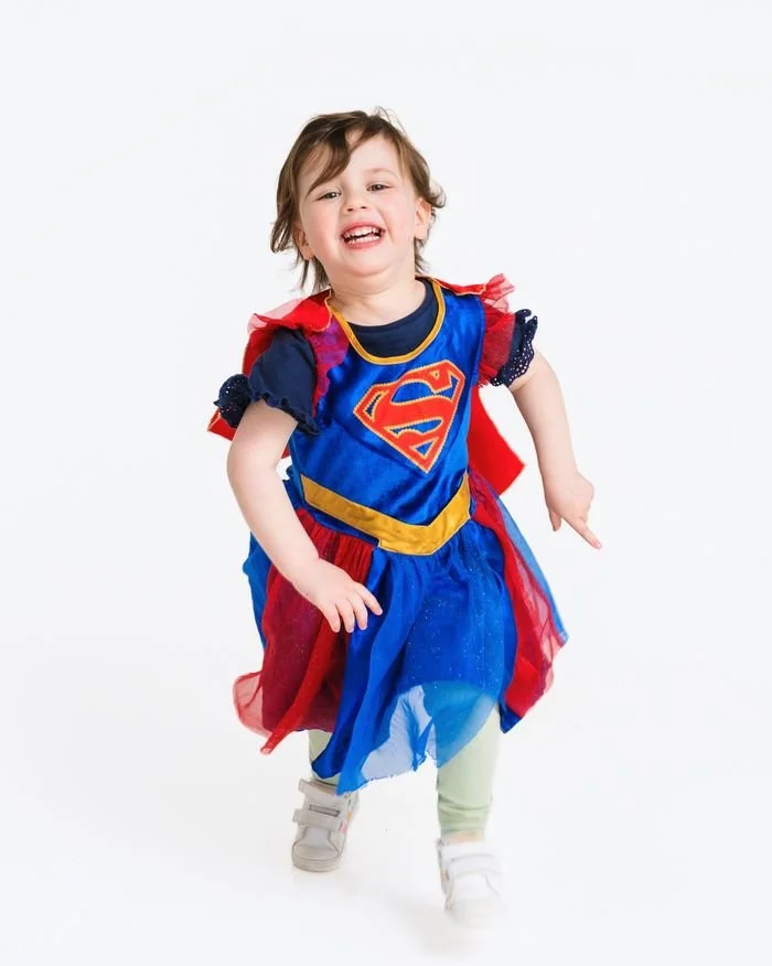 Wee girl running in a superhero costume
