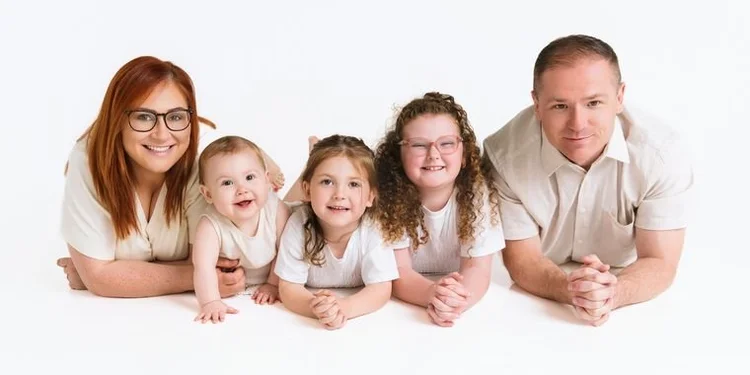 Family of five lying together in creams and white