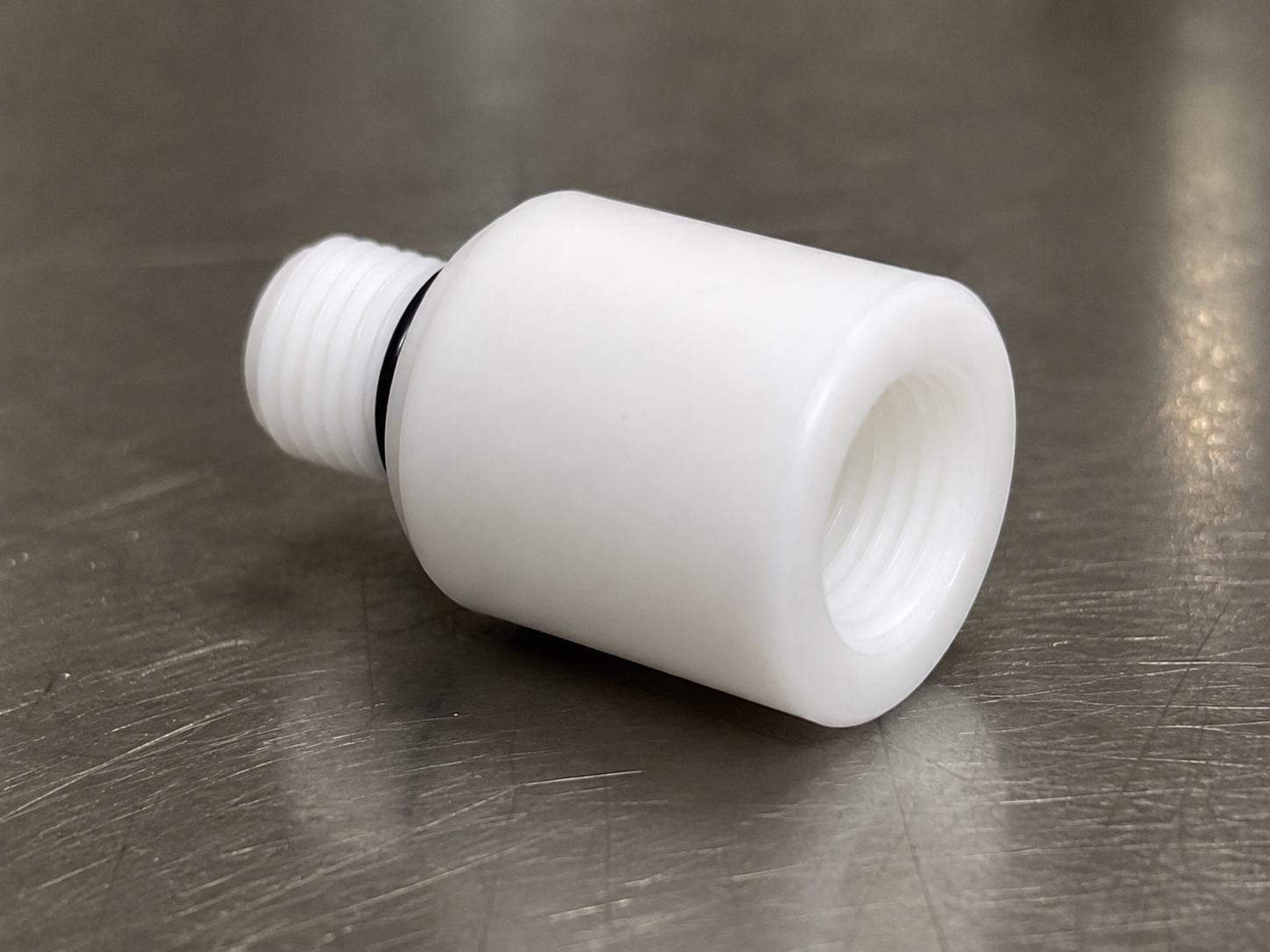 Delrin thread adapter for helium leak testing.