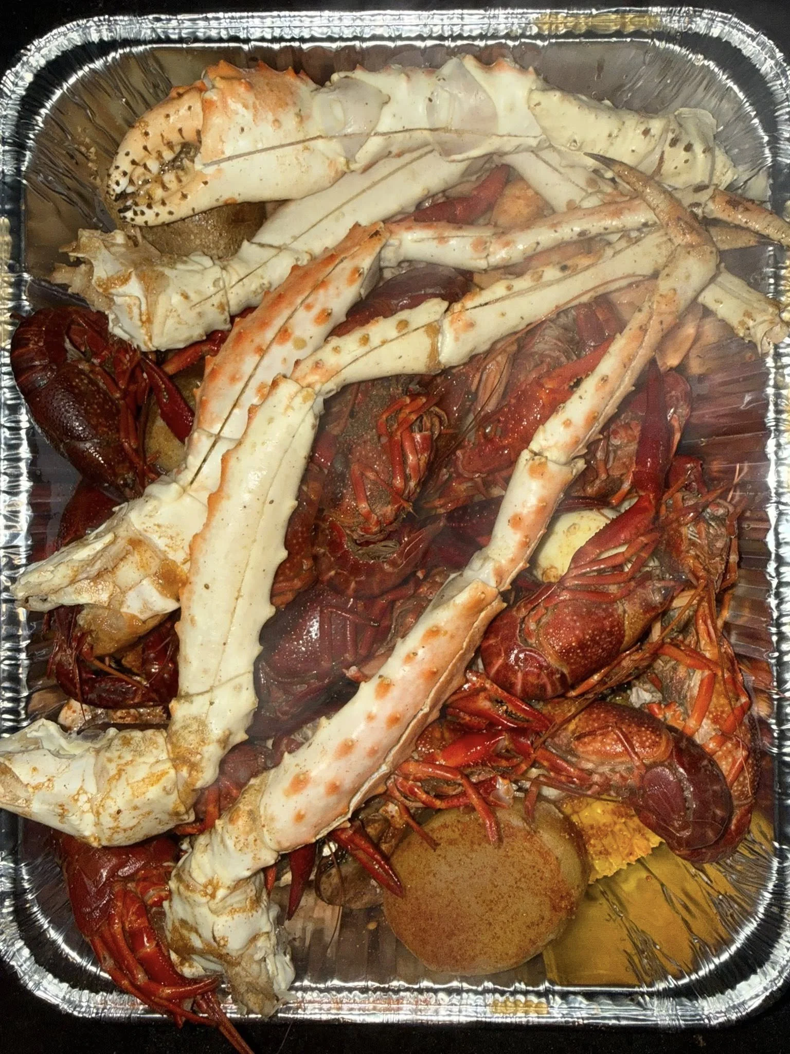 A tray of cooked seafood including lobster, crawfish, and crab.
