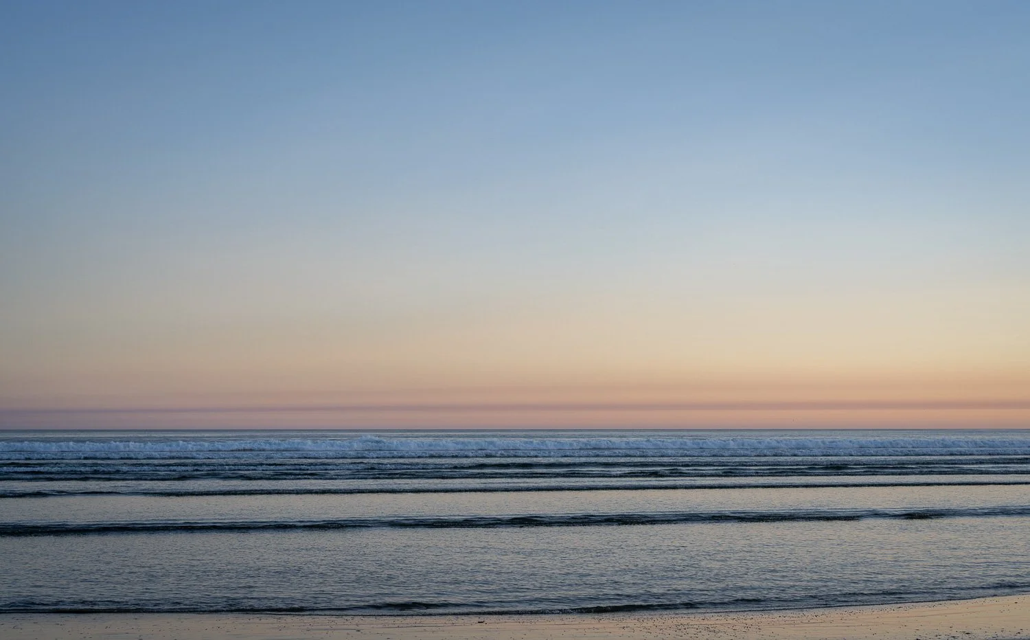 A minimal seascape at dusk off Tofino — smooth pastel ocean meeting a soft pink and blue sky at the horizon.