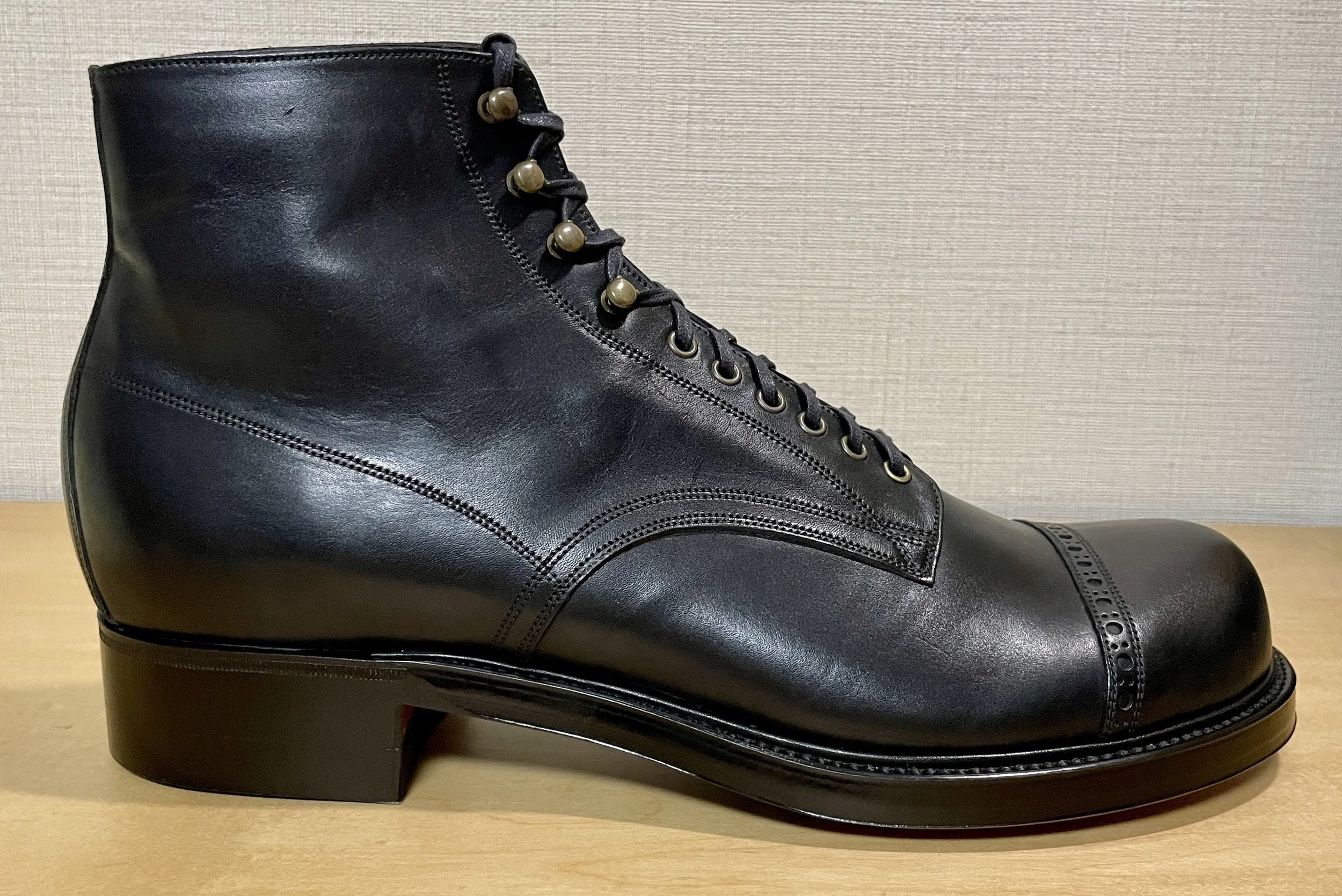 Black leather cap-toe work boot prototype inspired by early American service and work boots, shown in side view.