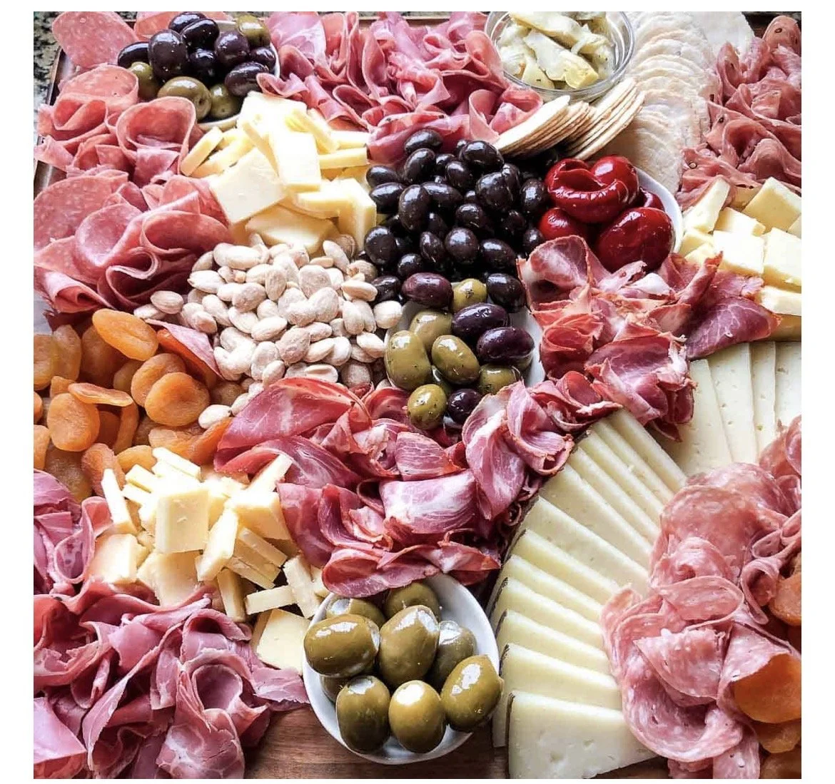 Assorted charcuterie with cheeses, cured meats, olives, and dried apricots.