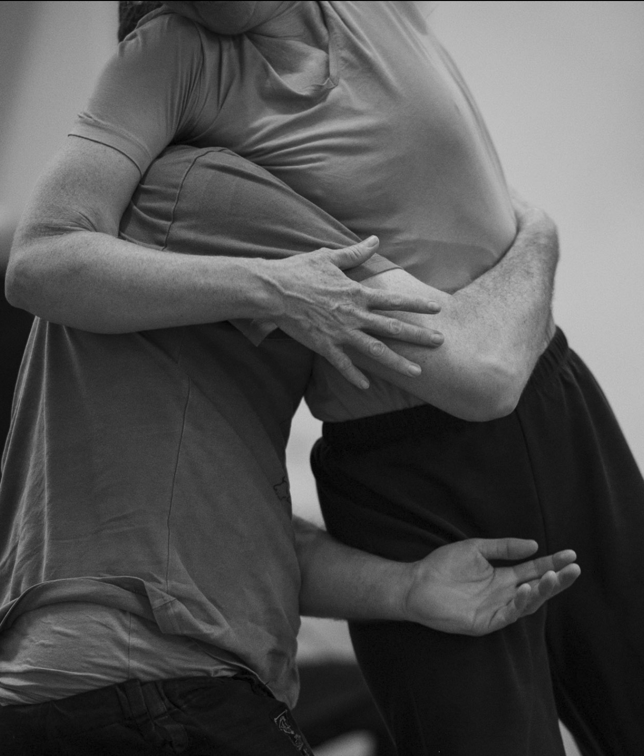 Two people are hugging each other closely, with one person's hand resting on the other's back. The photo is in black and white.