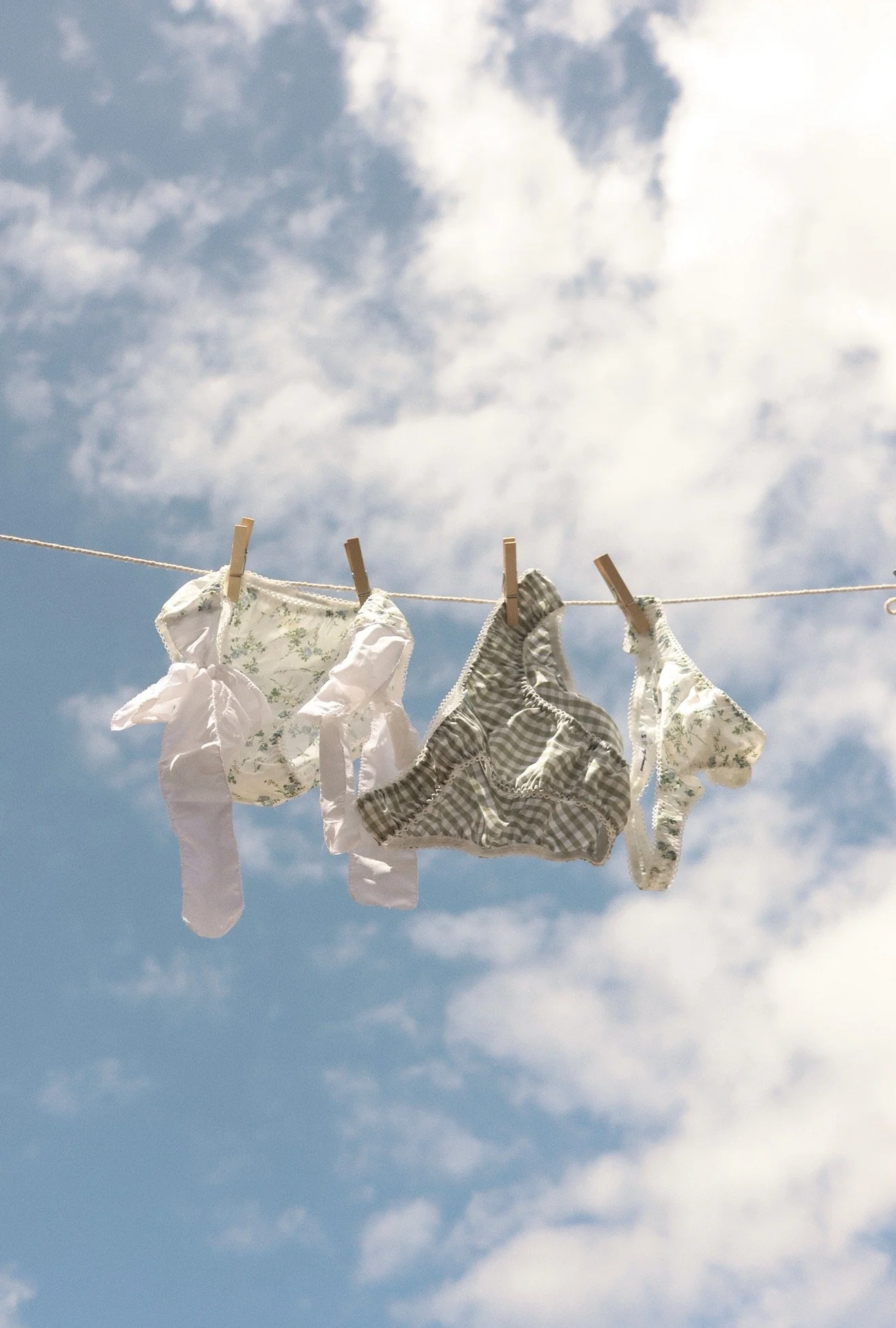 Clothes hanging on a clothesline with clothespins against a blue sky with scattered clouds