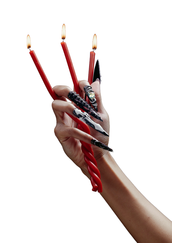 A hand with long, intricately designed nails holding three red candles in between her fingers.