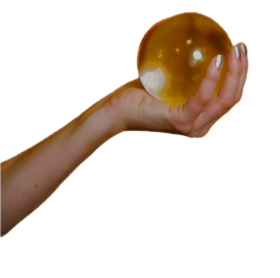 A hand holding a glass orb against a black background.