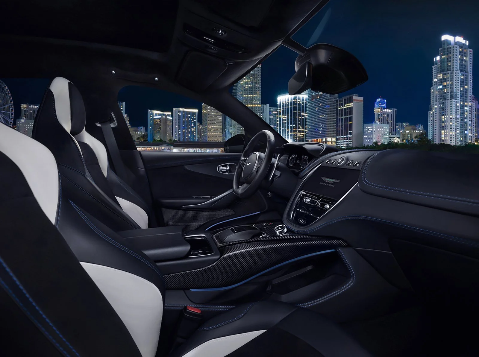 Elegant commercial advertising photography showcasing a luxurious Aston Martin automotive interior with a dramatic night time city skyline.