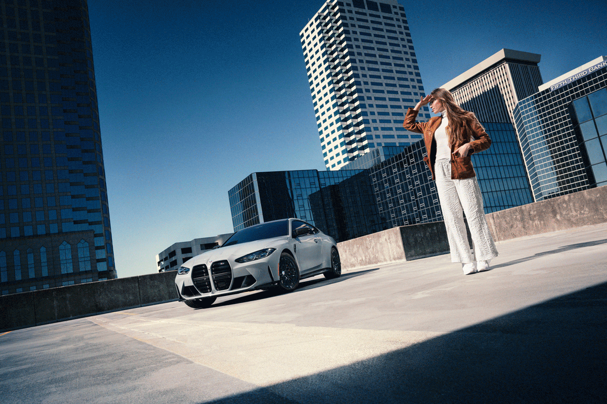 High-impact commercial advertising photography of a BMW M4 in an urban city rooftop with model.