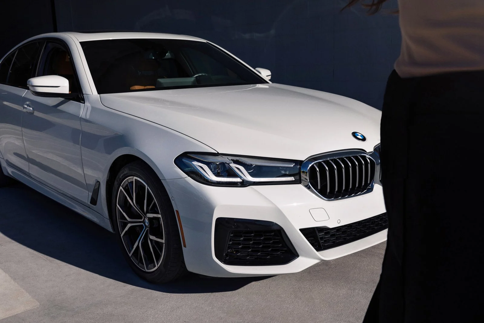 Commercial advertising lifestyle photography of a BMW 5-series sedan in a scenic city environment with styled talent.