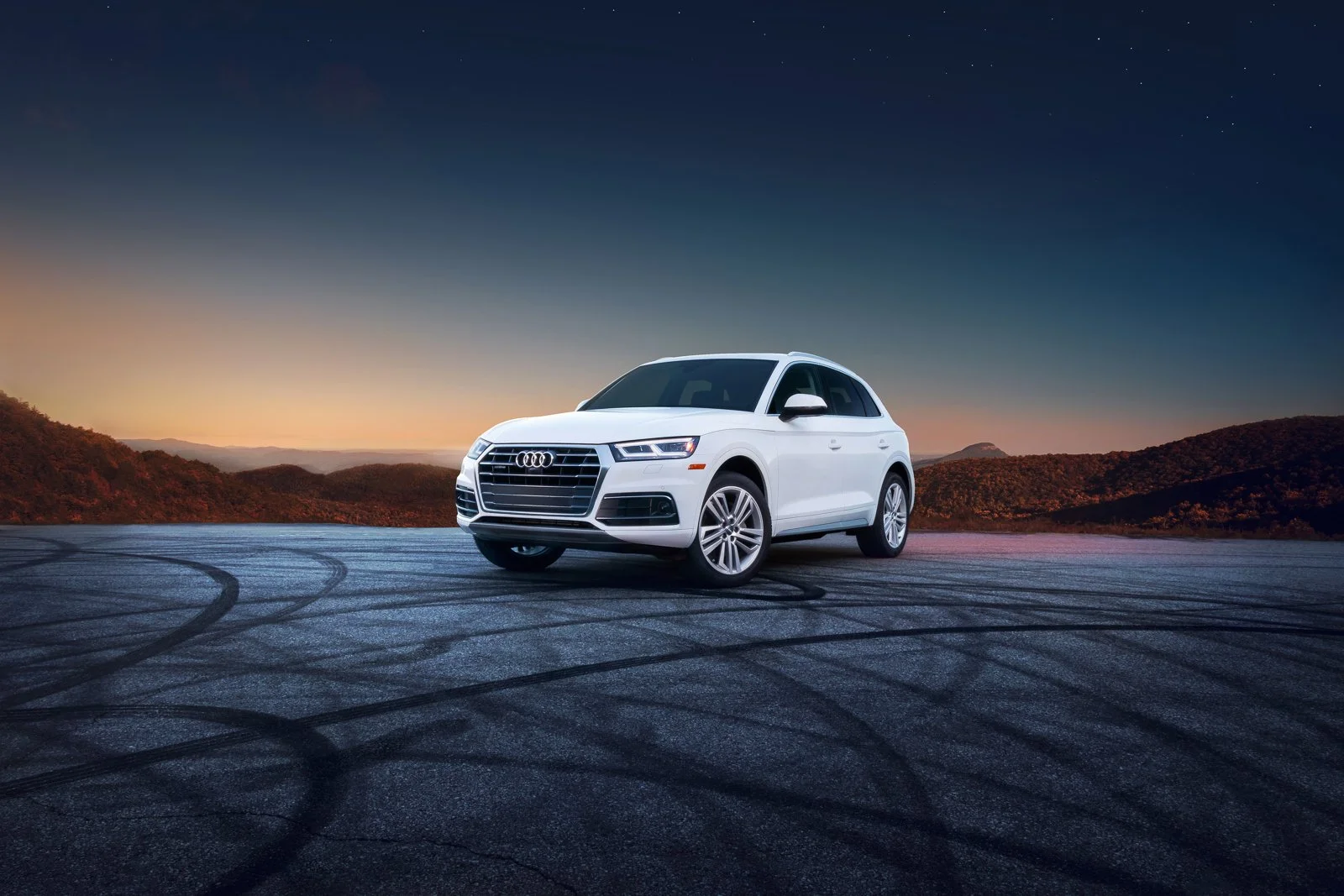 Dramatic commercial advertising photography of a Audi SUV with scenic mountain backdrop at sunset.
