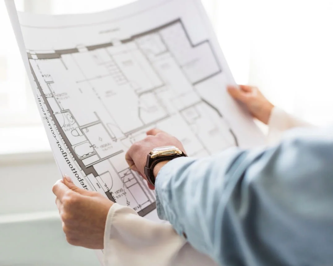 Person holding and examining a blueprint or floor plan of a building.