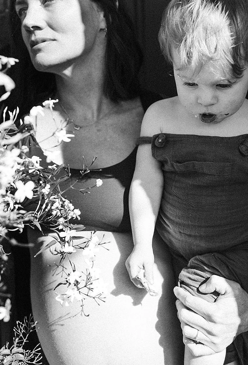Pregnant woman holding her young child, illustrating the ongoing journey of motherhood and matrescence.