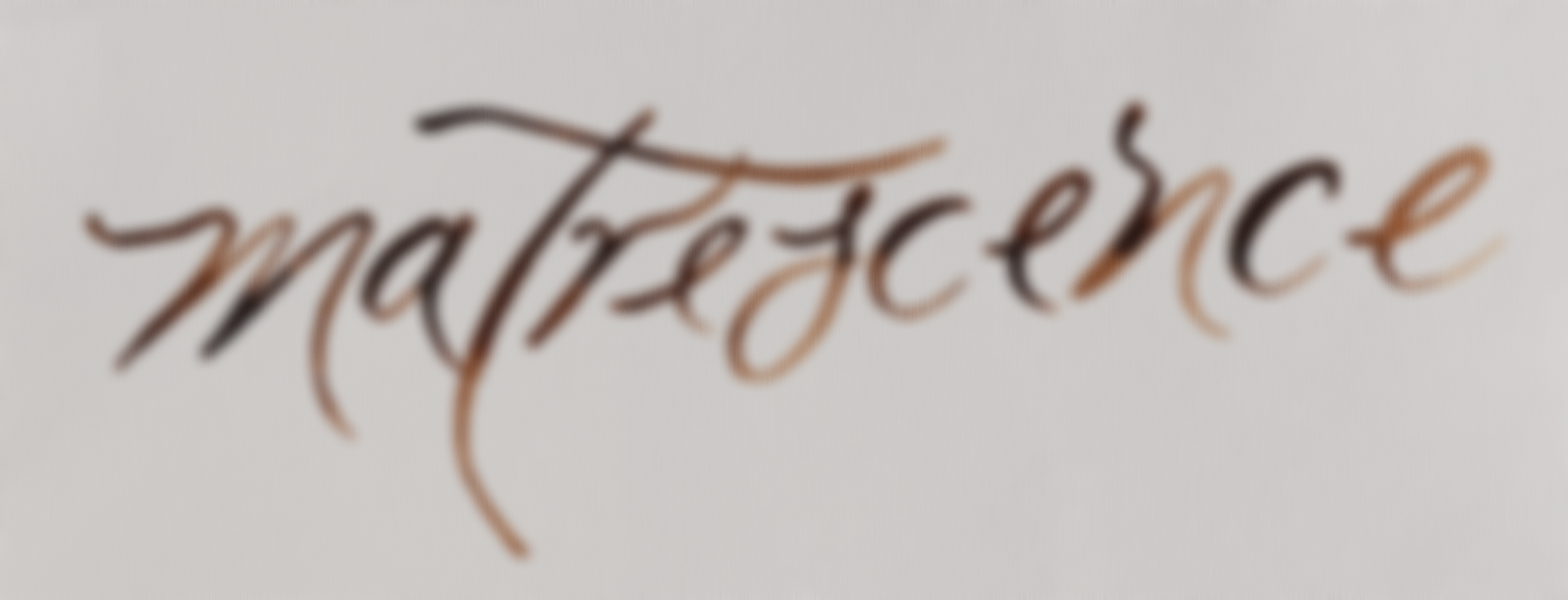 Blurred image of the word 'matrescence' written in cursive with brownish ink on a white background.