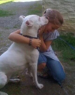 Ein Mädchen umarmt einen weißen Hund im Freien.