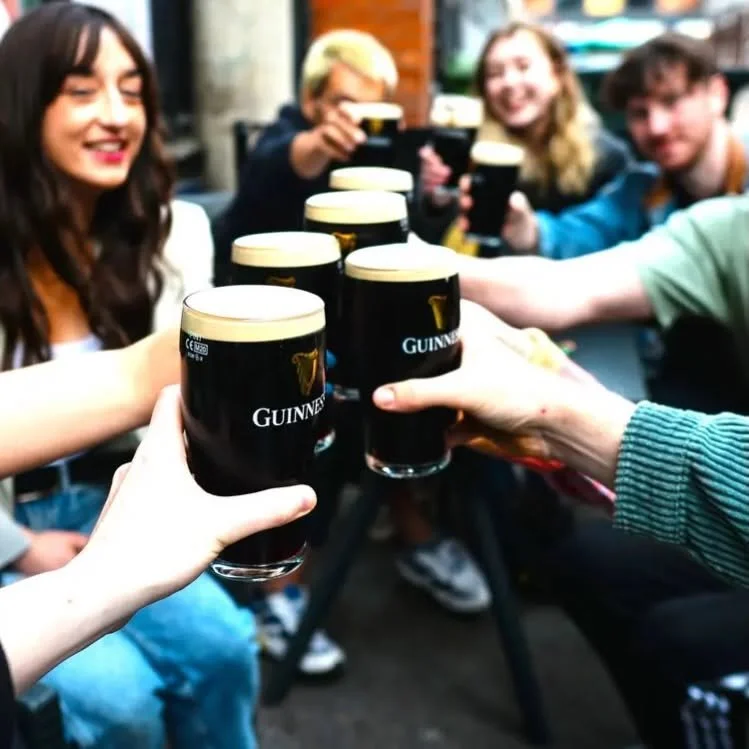 Friends toasting with pints of Guinness beer at a social gathering.