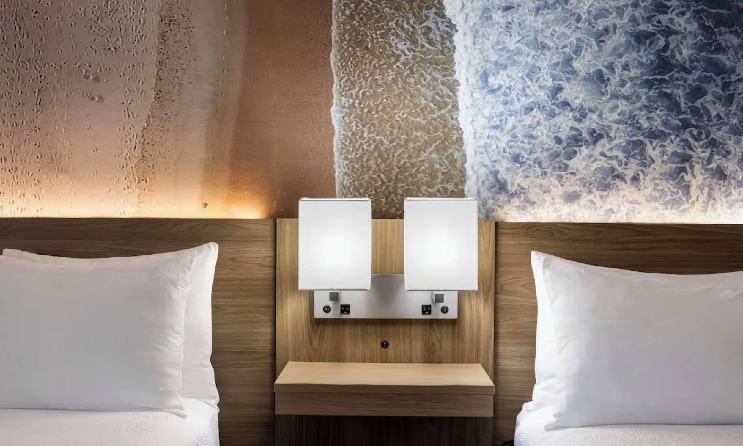 Modern hotel room with two beds and a beach-themed wall mural.