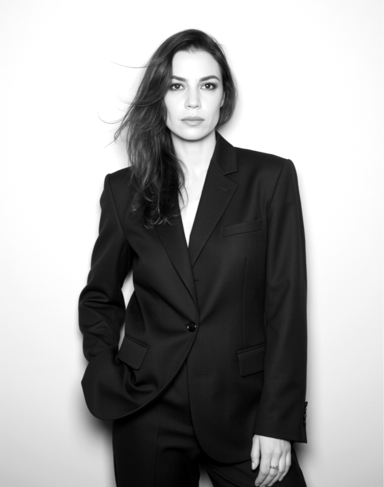 Black and white photo of a woman wearing a business suit, standing against a plain light background.