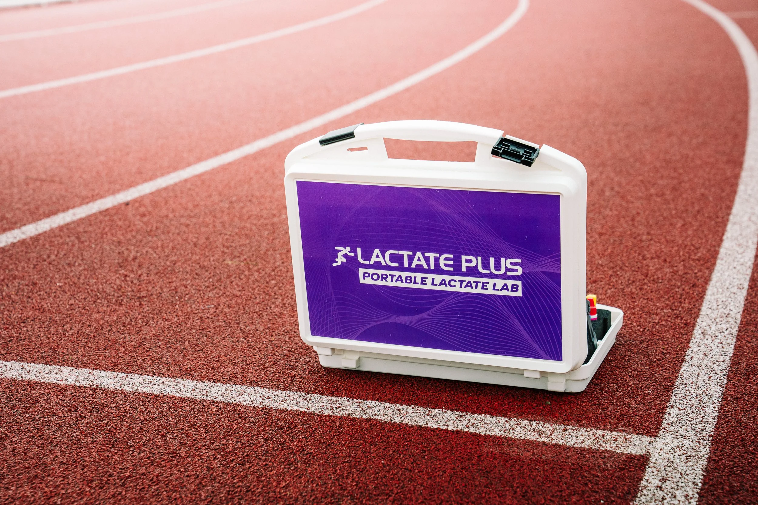 Portable lactate testlab op een atletiekbaan met een roodtrak en witte lijnen.