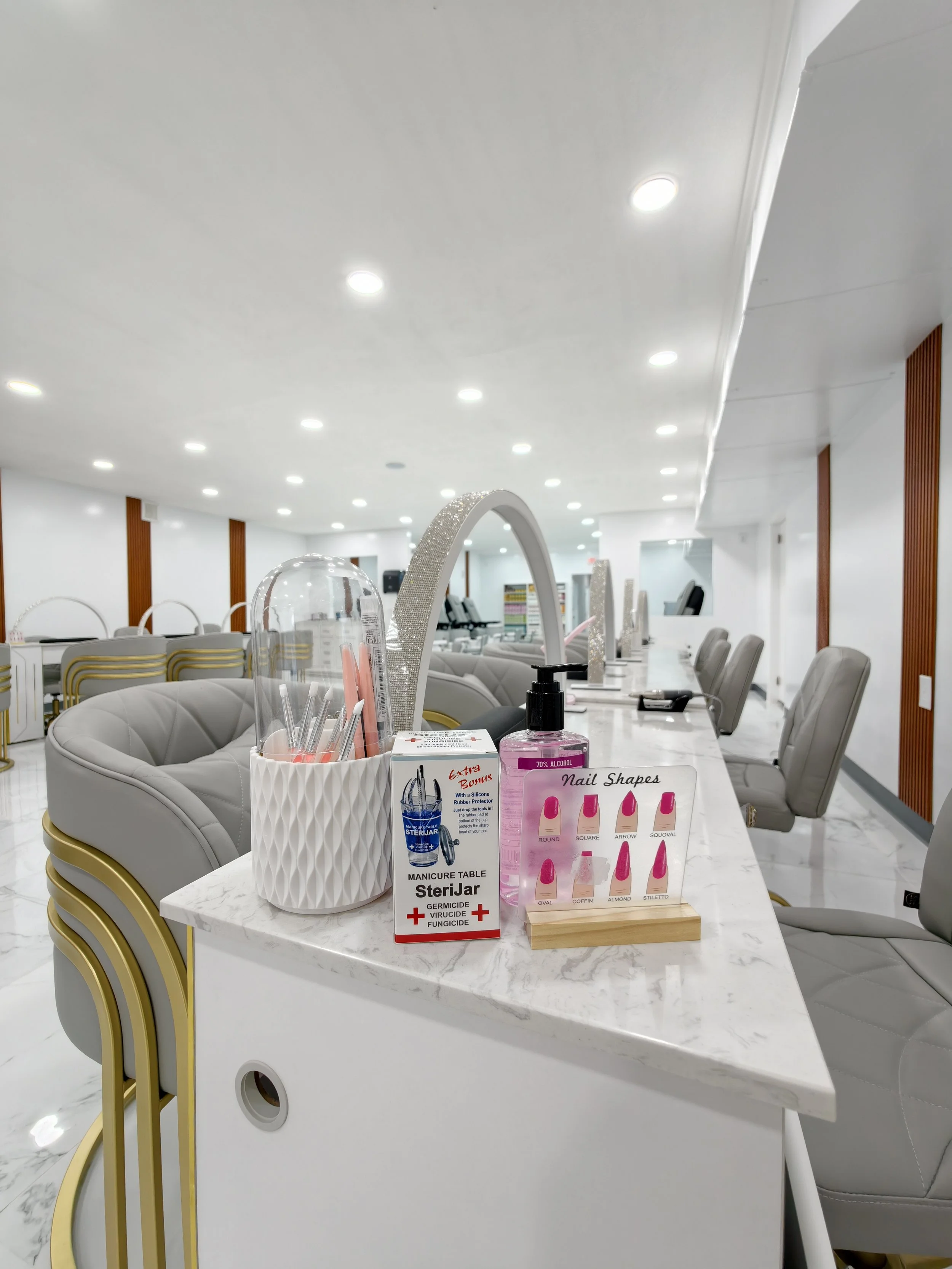 Beauty salon manicure station with chairs, nail polish displays, hand sanitizer, and informational signs.