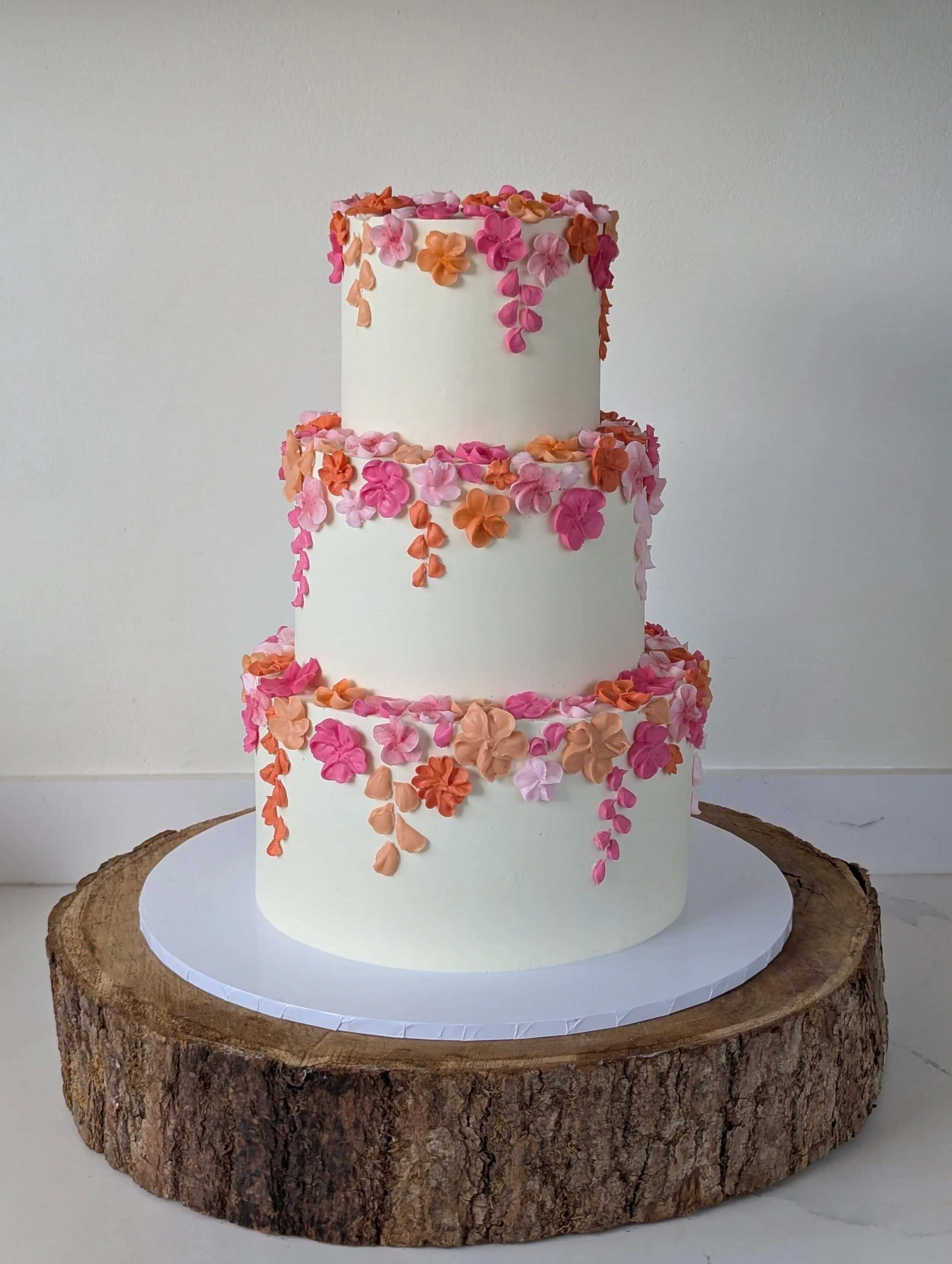 Three tier wedding cake with piped edible flowers.