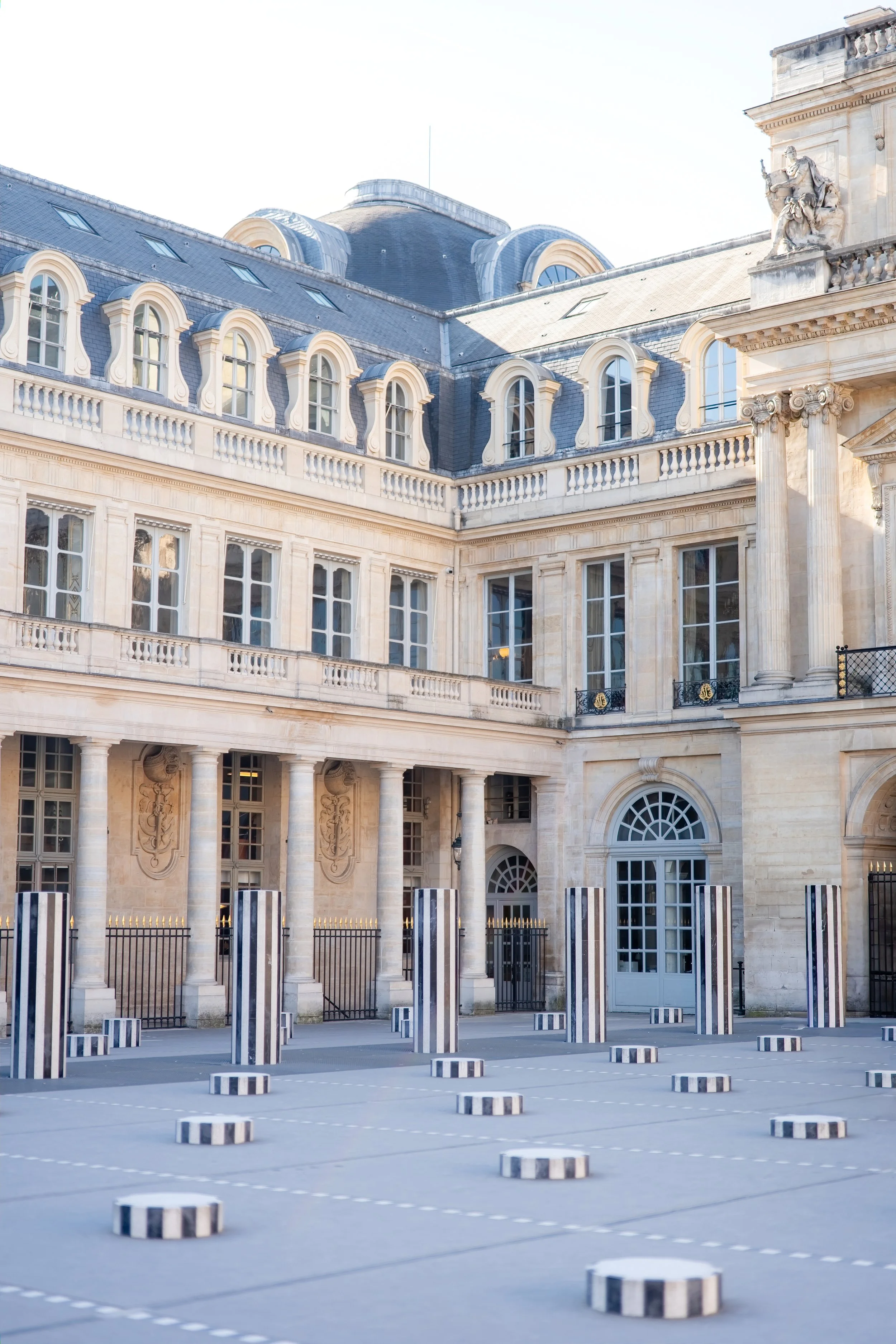 Palais Royal showing off with it's classical architecture, including arched windows, ornate stone carvings, and a rooftop statue. 