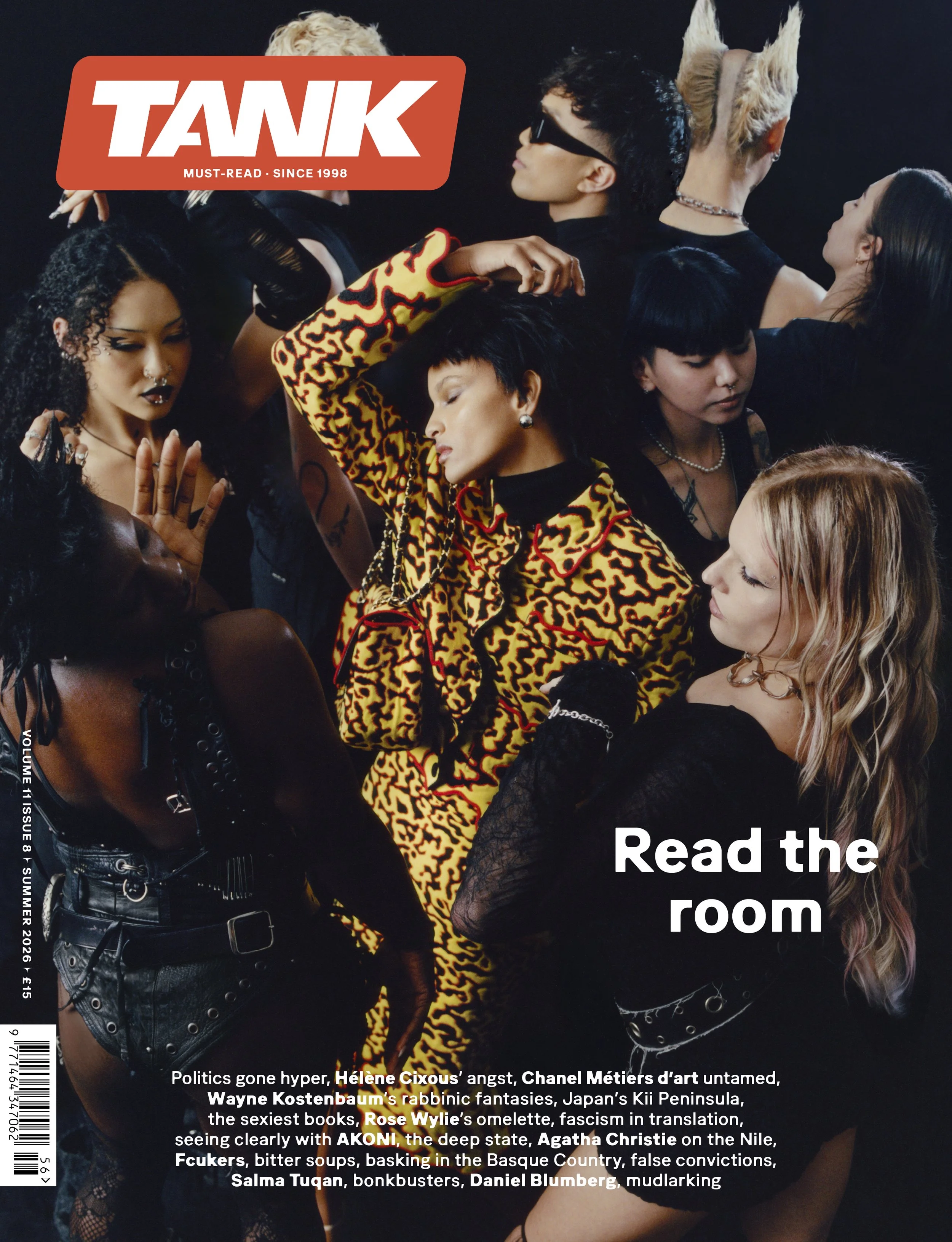 A group of diverse young women with edgy clothing and hairstyles, posing together in a studio against a black background for a fashion magazine cover.