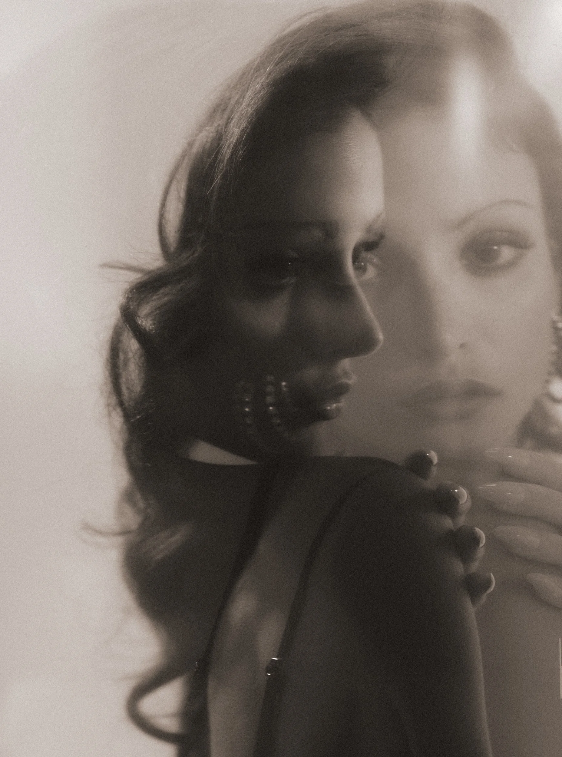 Black and white close-up of a woman's face, with focus on her eye, nose, and lips, and her hair styled with loose curls.