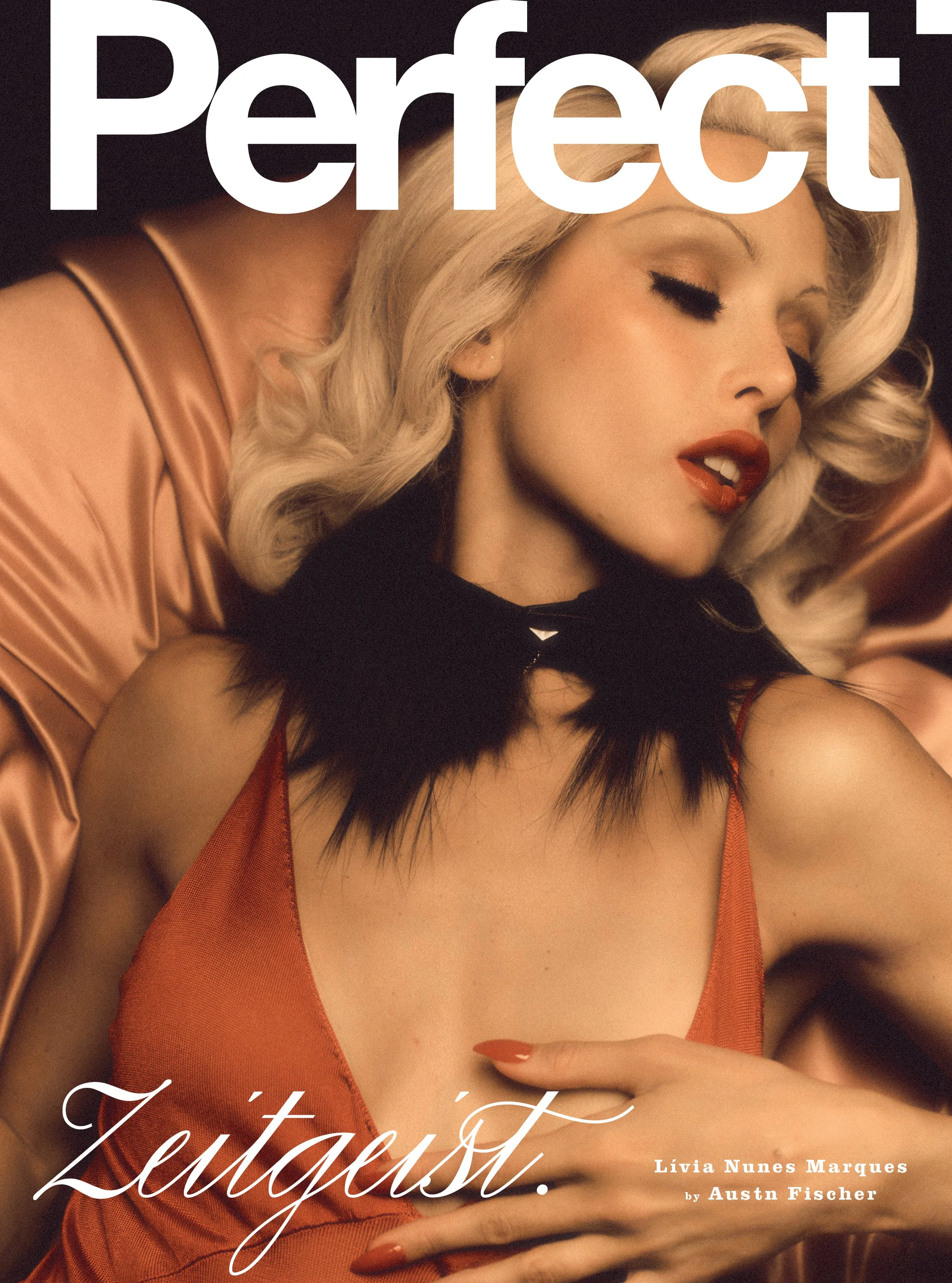 Close-up of a woman with platinum blonde hair and red lipstick, posing with her eyes closed. She is wearing a satin, orange-colored top and has a black fur collar. Large white text overlay says "Perfect" at the top, and smaller white text at the bottom reads "Lívia Nunes Marques by Austn Fischer."