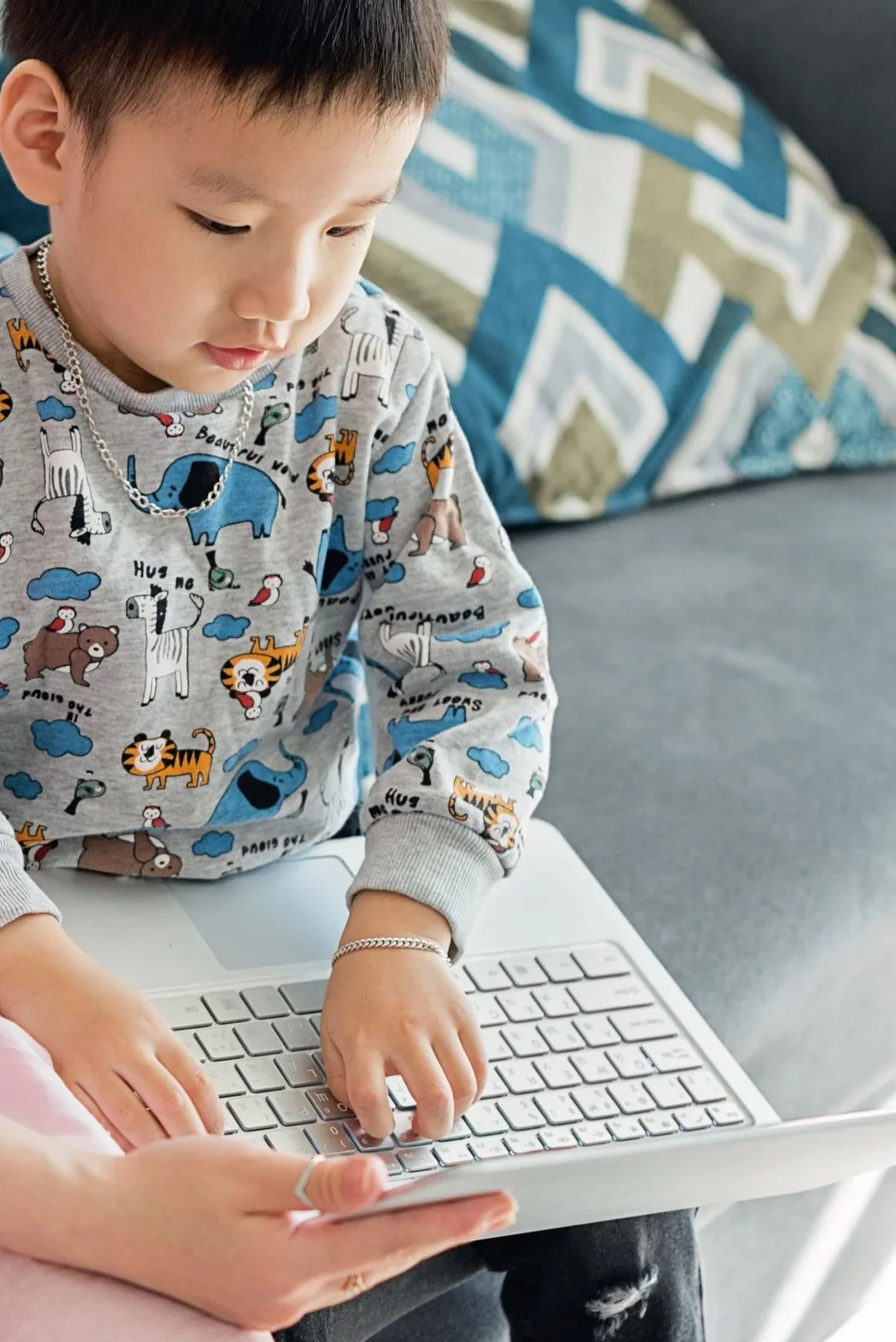 Primary-age child using a laptop with adult support.