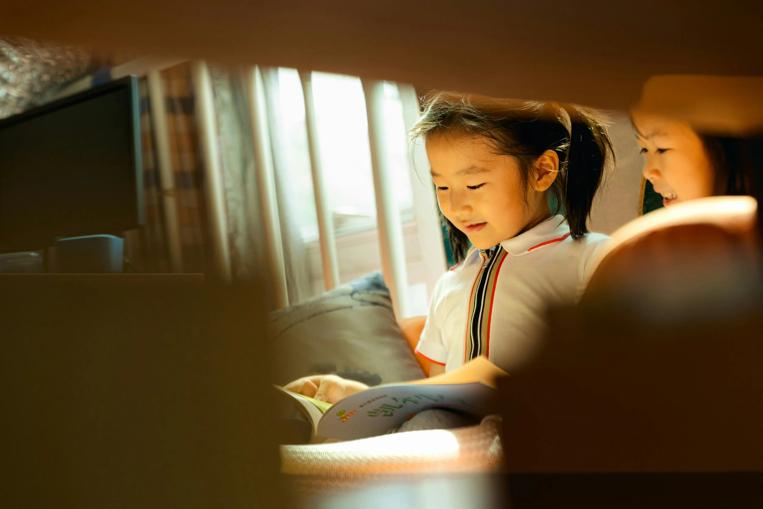 Two primary-age children reading a book together.