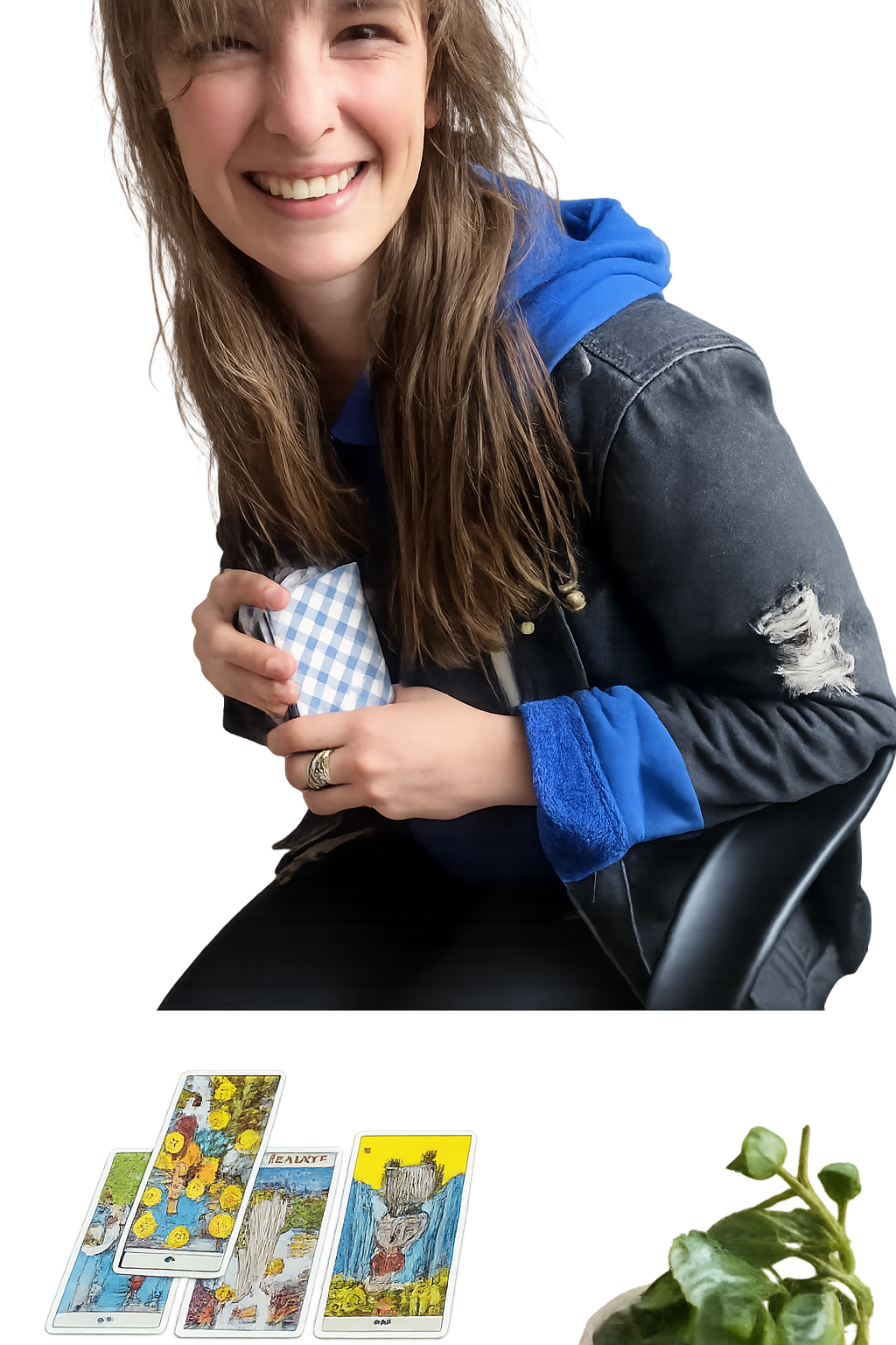 A young woman with long brown hair smiling and sitting at a table with tarot cards laid out, holding a checkered cloth bag. She is wearing a black jacket with ripped sleeves and a blue hoodie underneath.