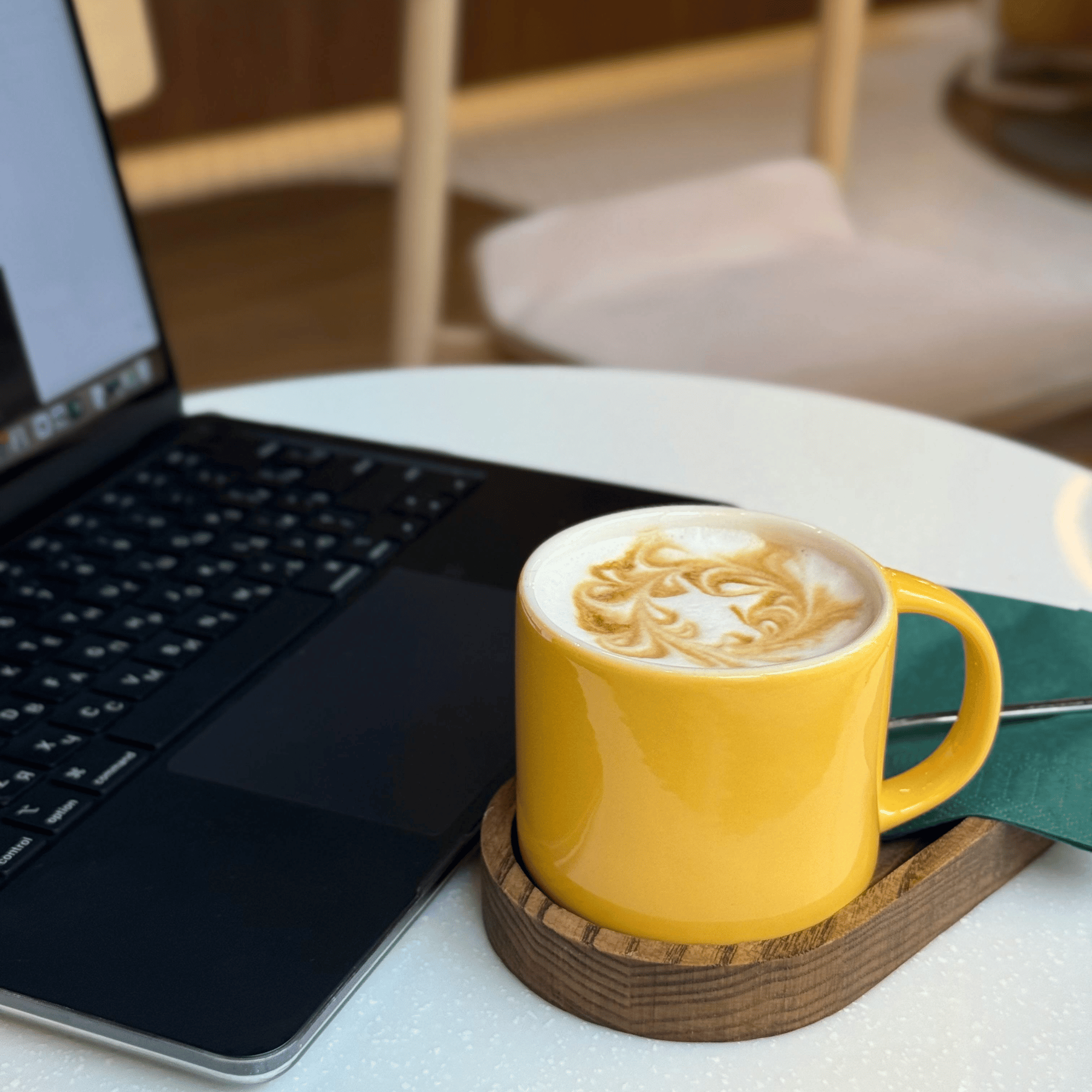 Close-up of a yellow coffee cup and open laptop on a desk, representing an online strengths coaching session