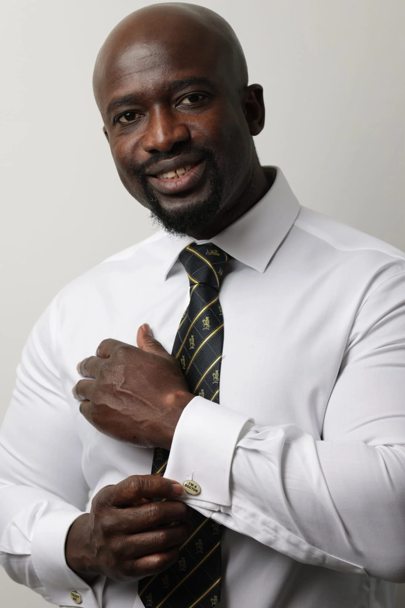 Doctor Boakye-Acheampong Ishmail. A man wearing a white dress shirt, patterned tie, and a button that says 'I'm a doctor' and a pin that says 'trust me'.