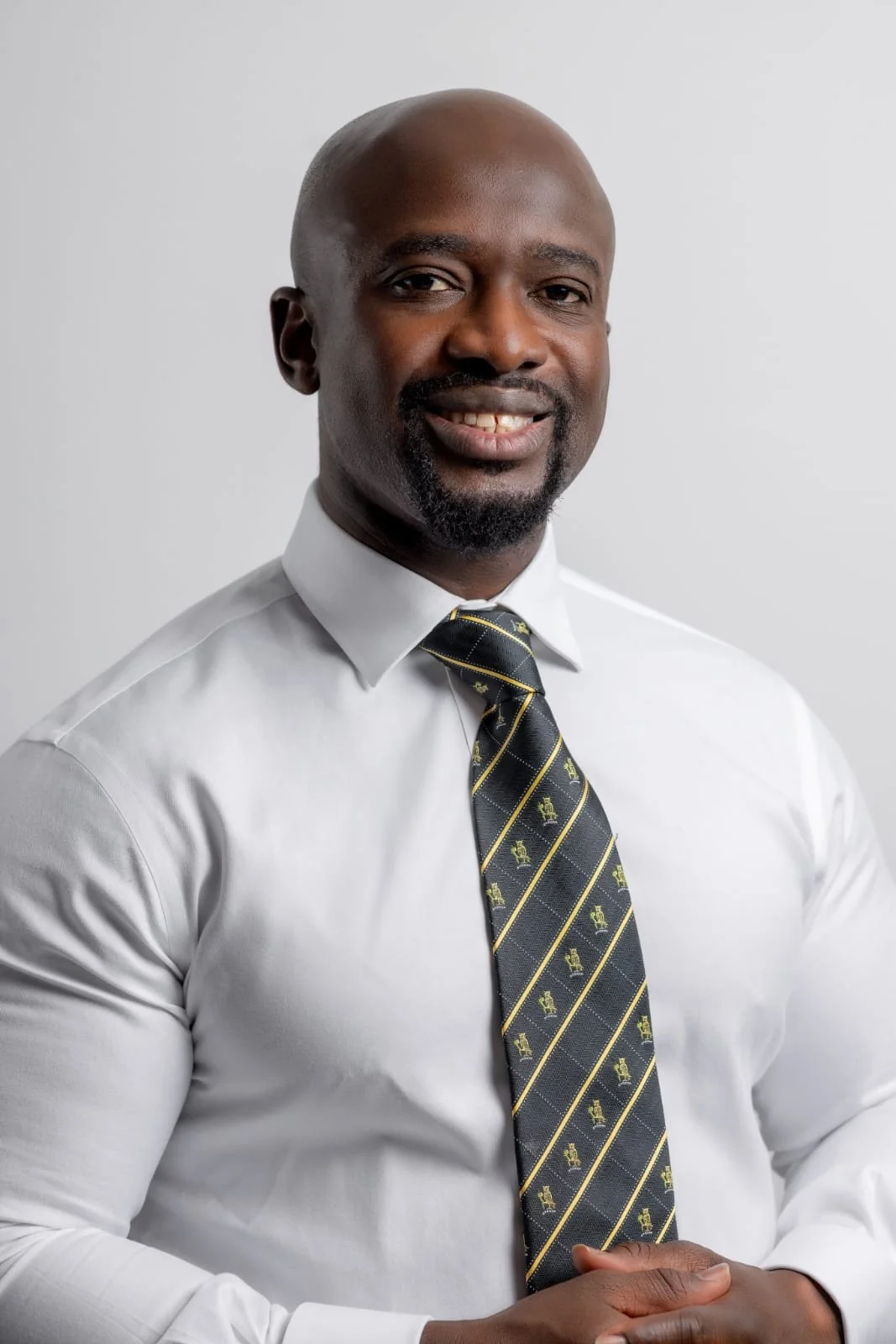 Doctor Boakye-Acheampong Ishmail. A man wearing a white dress shirt, patterned tie, and a button that says 'I'm a doctor' and a pin that says 'trust me'.