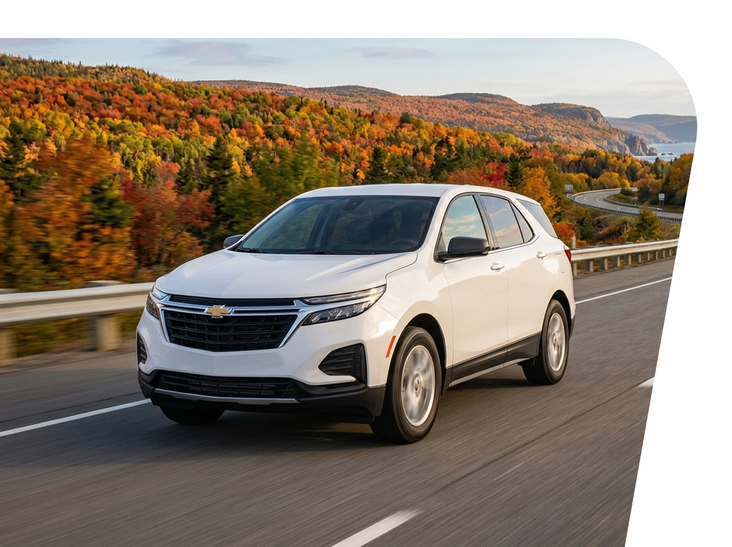 A white Chevrolet SUV driving on a highway with colorful fall foliage on hills in the background.