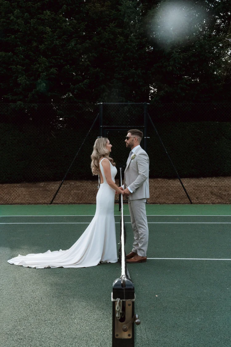 Bride and groom standing together on the tennis court