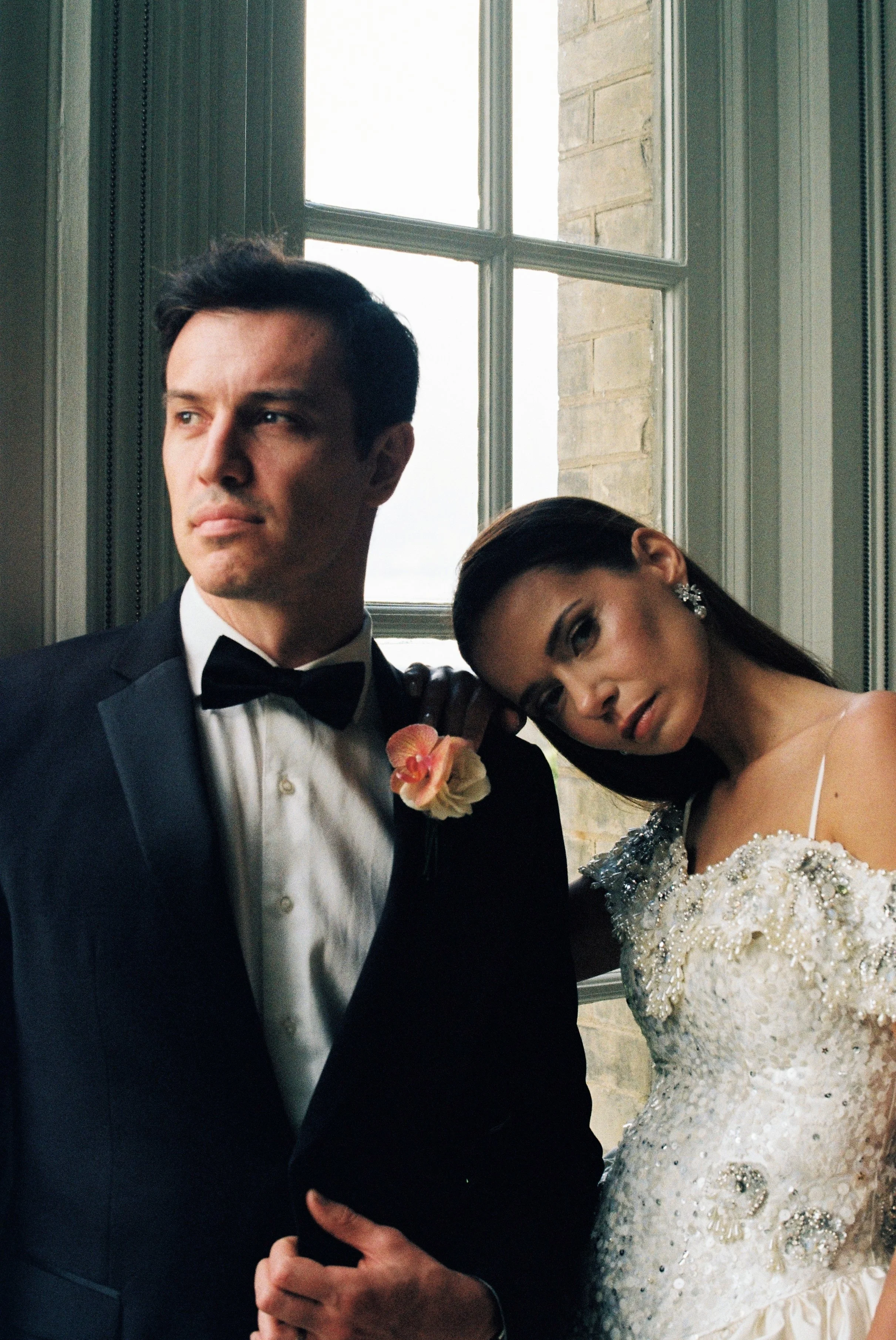Bride and groom posing beside a window at Hedsor House, photographed on 35mm film