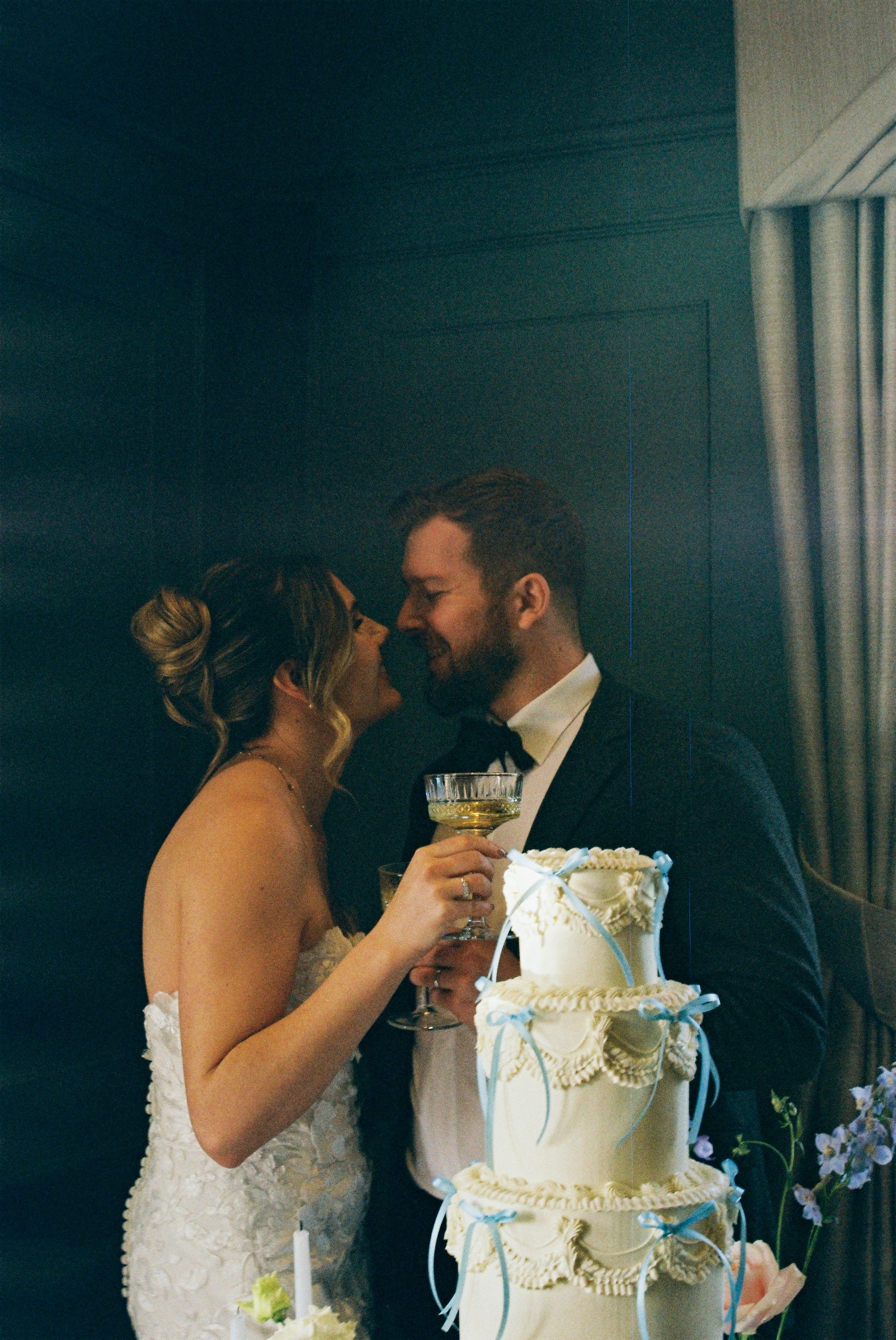 A bride and groom stand close together and share a kiss at their wedding reception at Downham Hall, Essex.