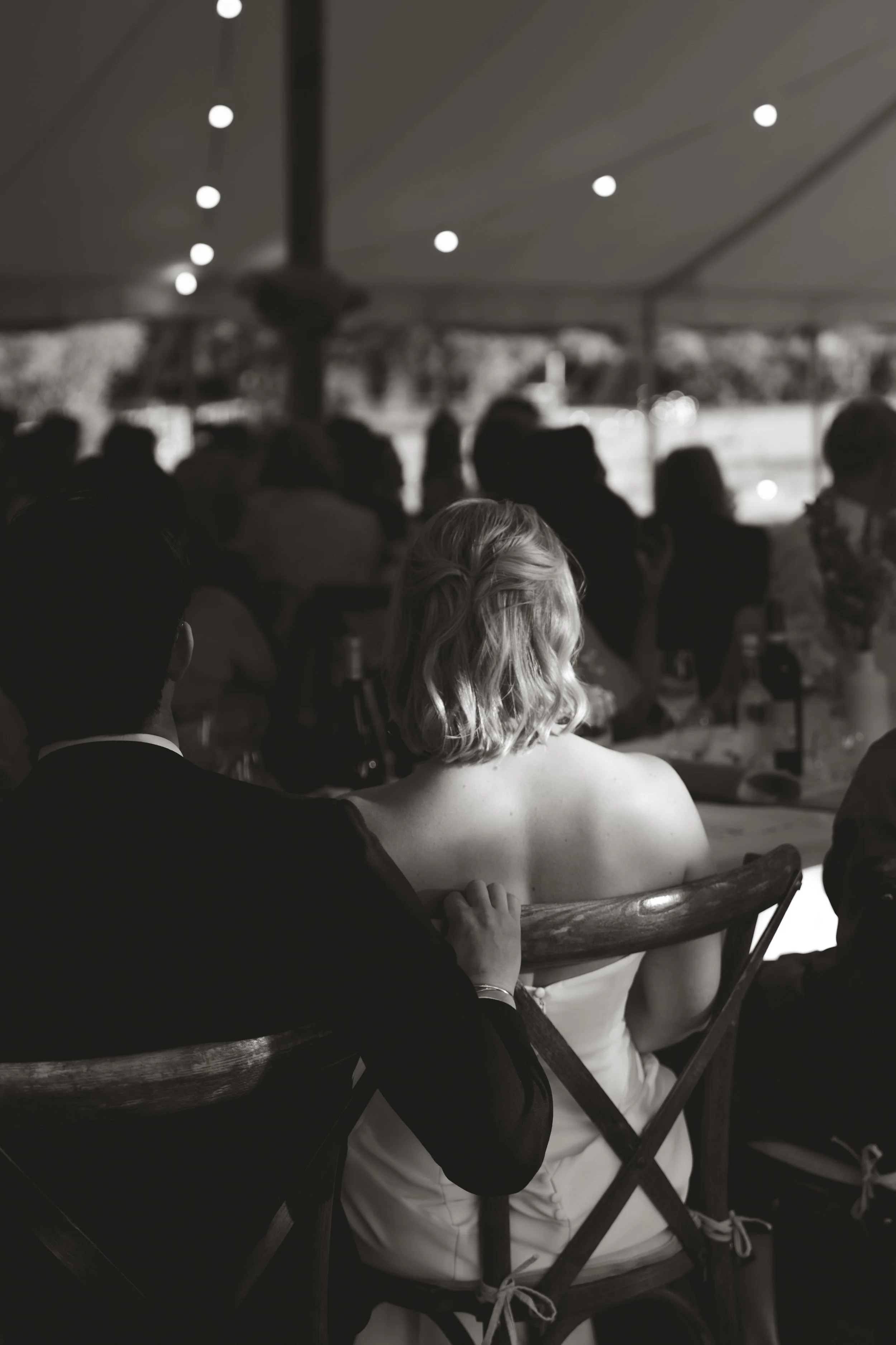 Bride and groom seated together beneath a marquee during their outdoor wedding reception