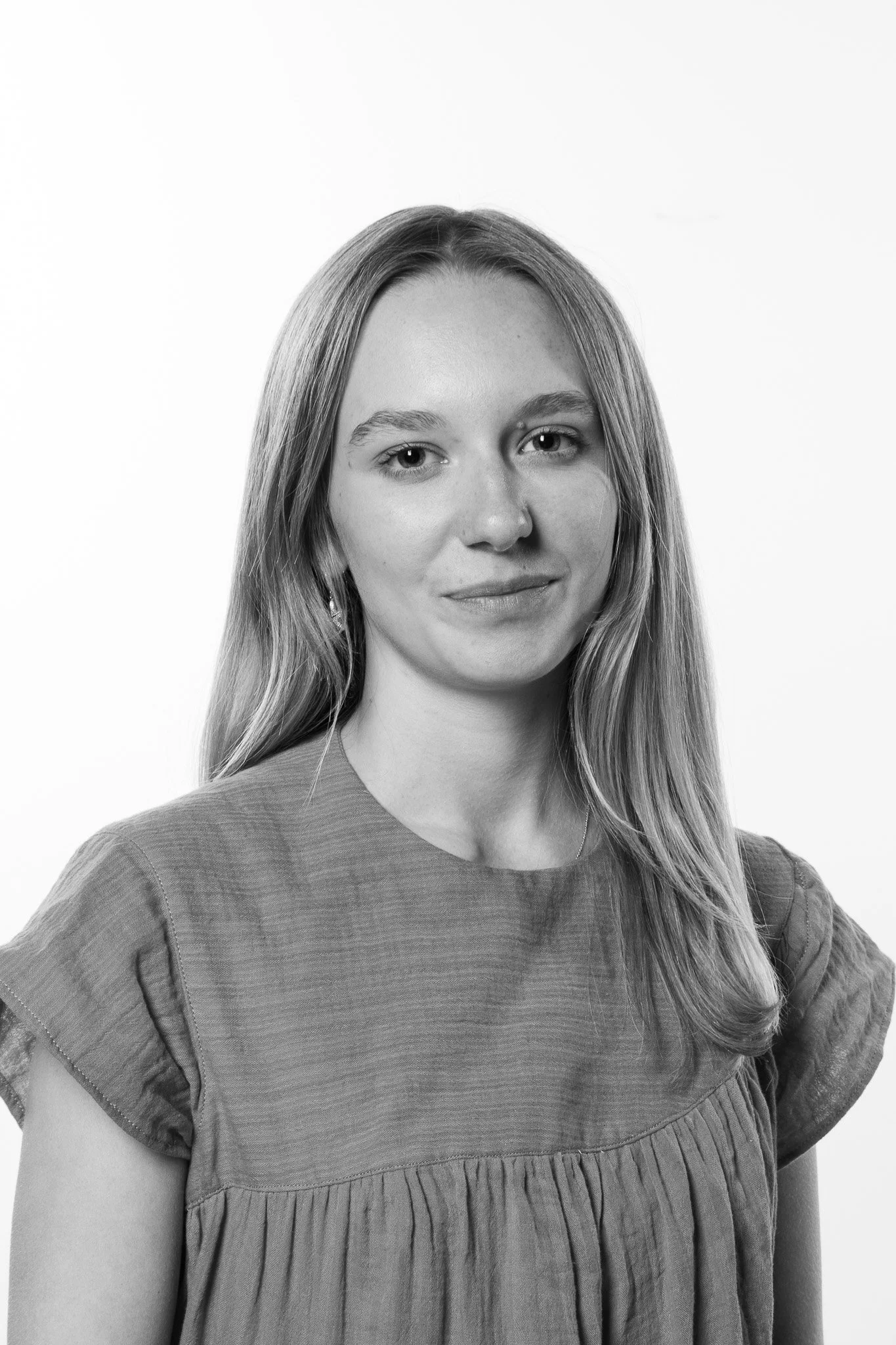 Black and white portrait of a young woman with long hair, wearing a textured short-sleeve top.