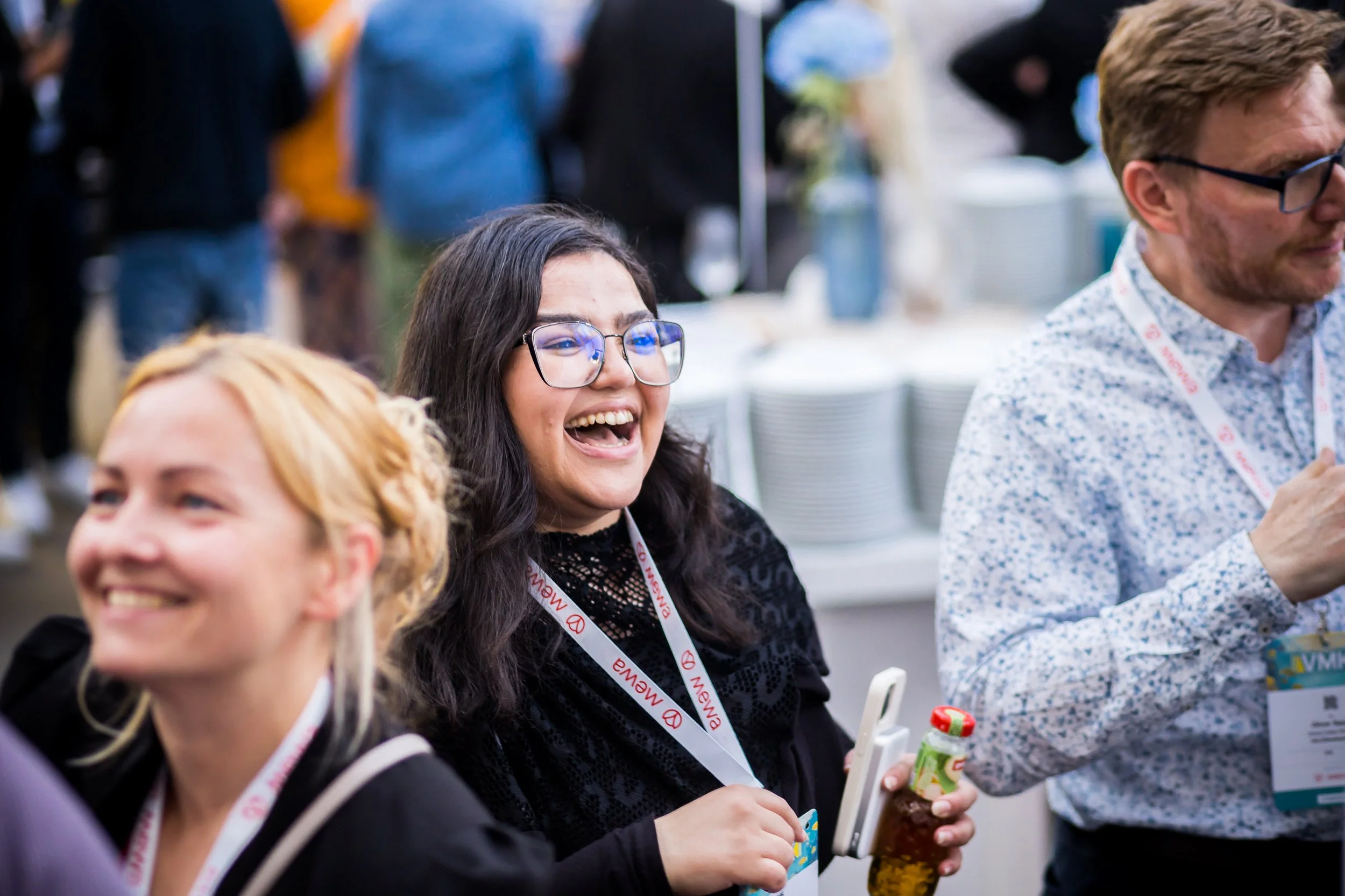 Menschen, die auf einer Veranstaltung lachen und sich unterhalten, mit Lanyards um den Hals.