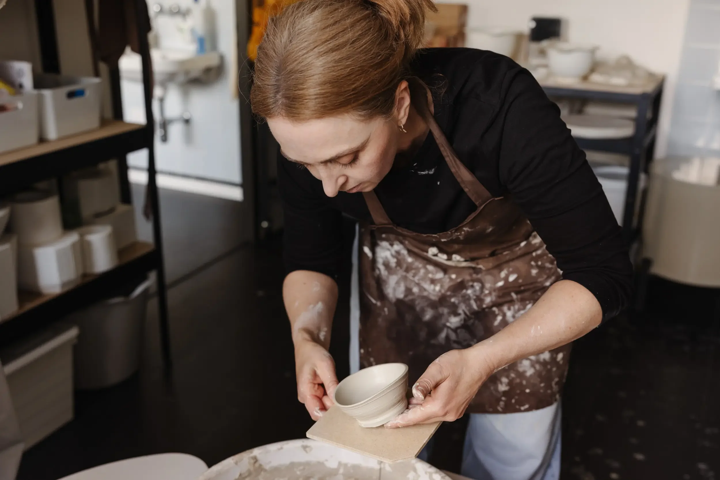 Eine Frau beim Töpfern in einem Workshop. Sie formt mit ihren Händen einen Tonkrug.