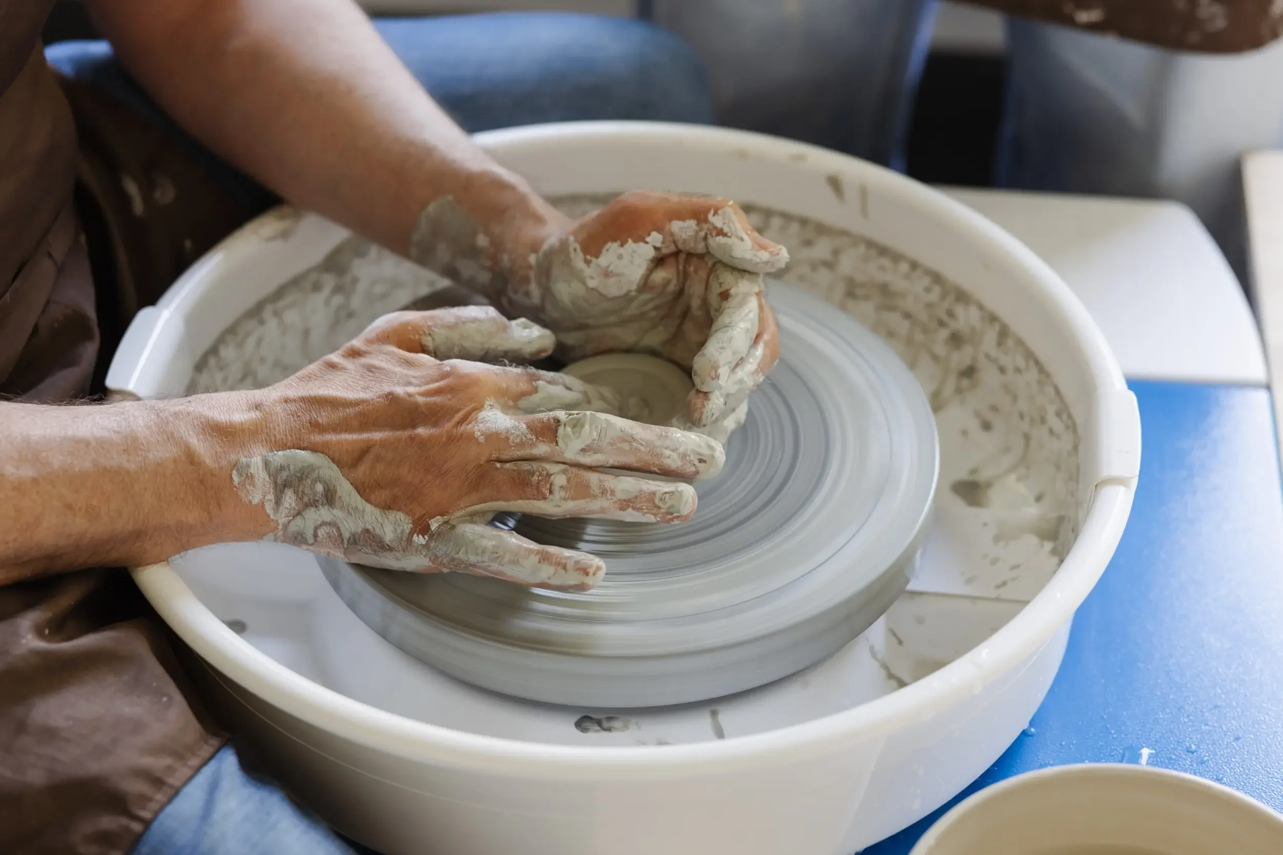 Handwerker formt Ton auf einer Drehscheibe in einer Werkstatt.