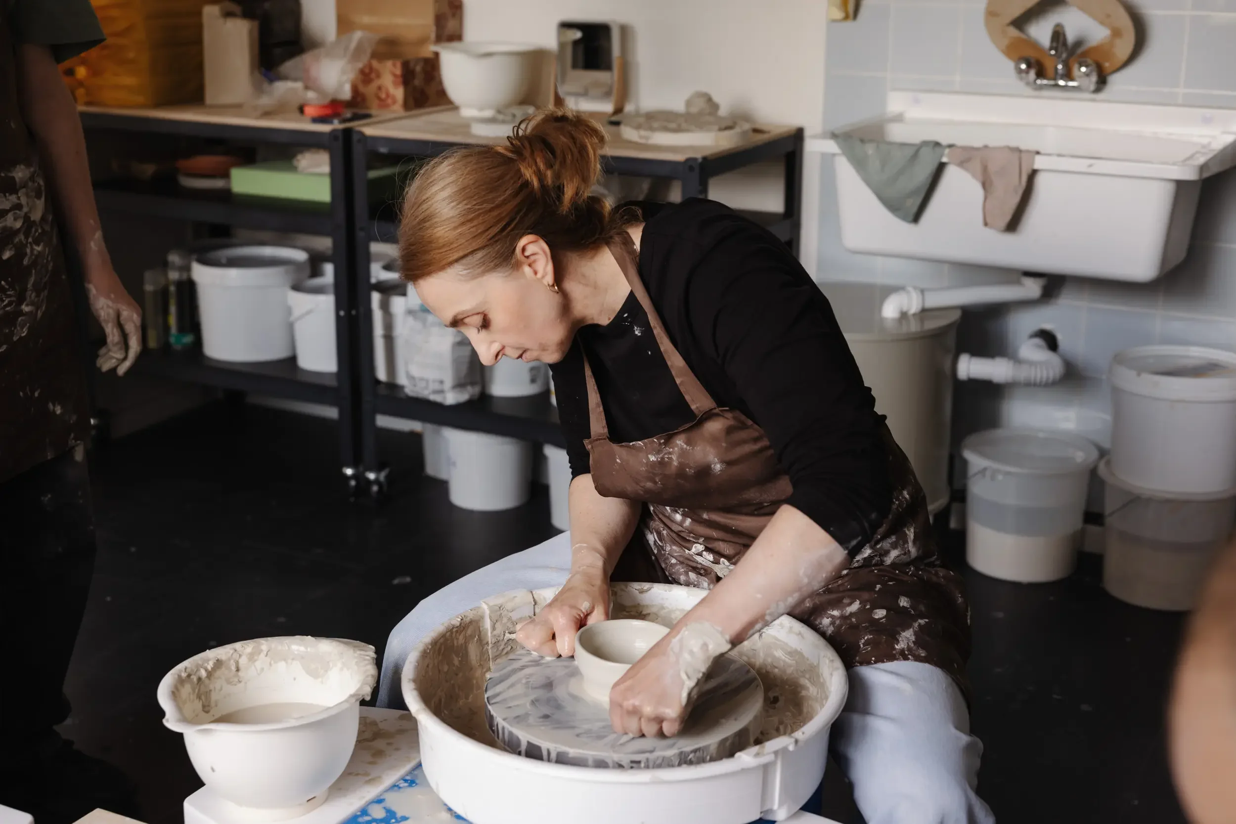 Frau beim Töpfern in einer Werkstatt mit Ton und Tonwaren auf einem Tisch