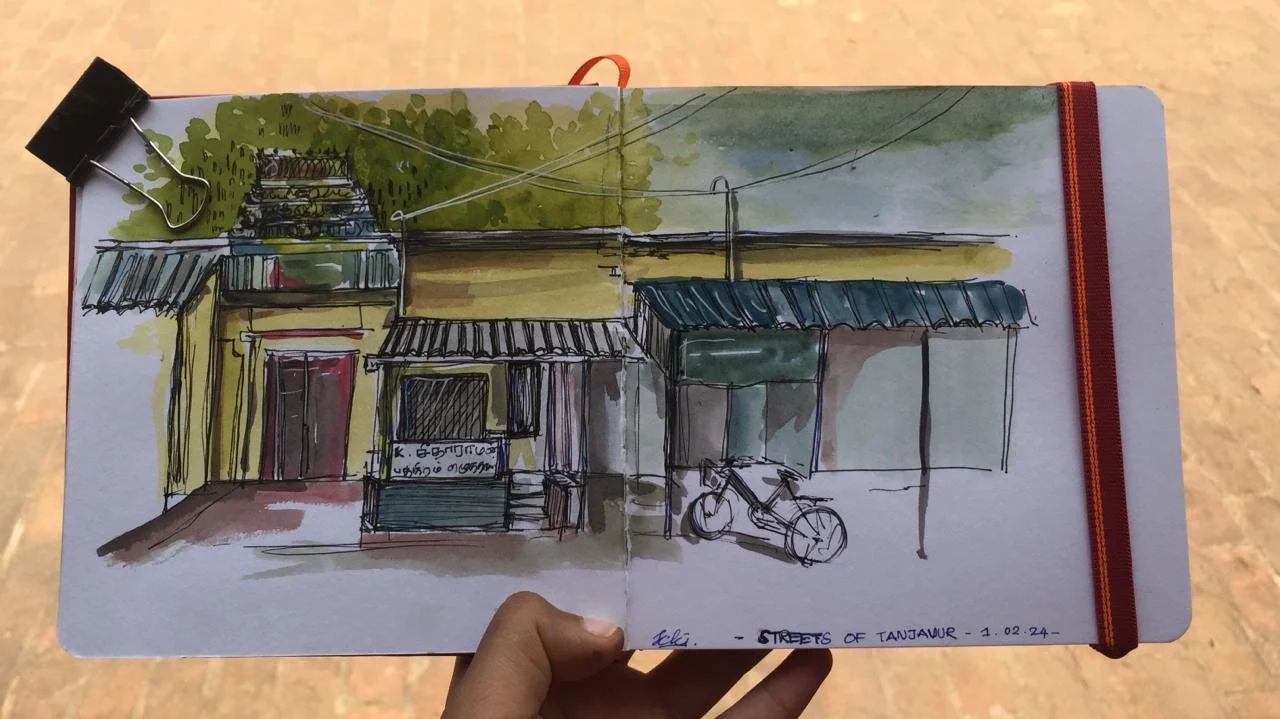 Sketch of a street scene in Tanjavur, India, showing a storefront with a tin roof, a bicycle parked outside, and trees in the background, with the date 1.02.24 written at the bottom.